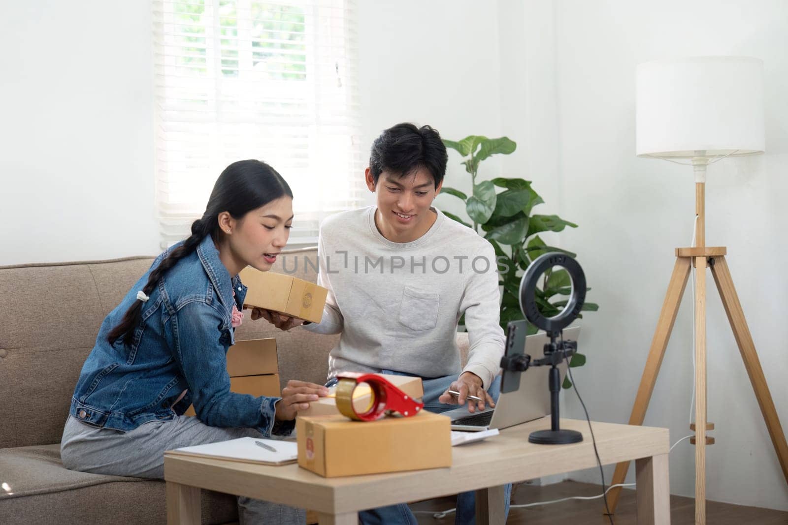The couple collaborates on their business strategy at their home office, excitedly sharing ideas and reviewing their latest shipments of products while surrounded by packed boxes.