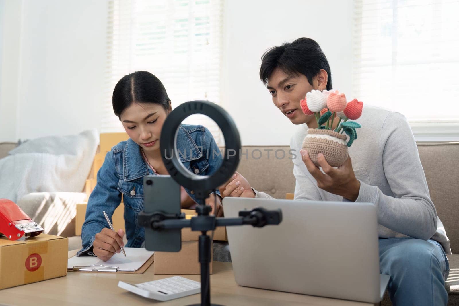 A young couple discusses their business ideas, focusing on showcasing creative products during a team meeting at home. Their joyful interaction signifies teamwork and entrepreneurship.
