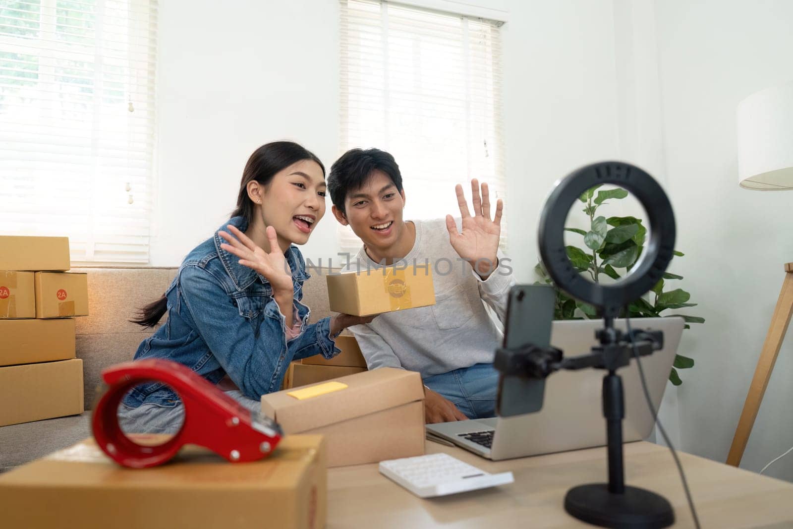 The couple waves to their audience during a live stream, showcasing their latest products and sharing insights about their entrepreneurial journey, fostering connection with their viewers.