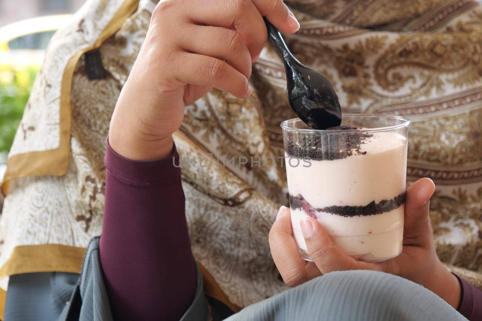 A person savors a layered dessert with a spoon at a cafe.