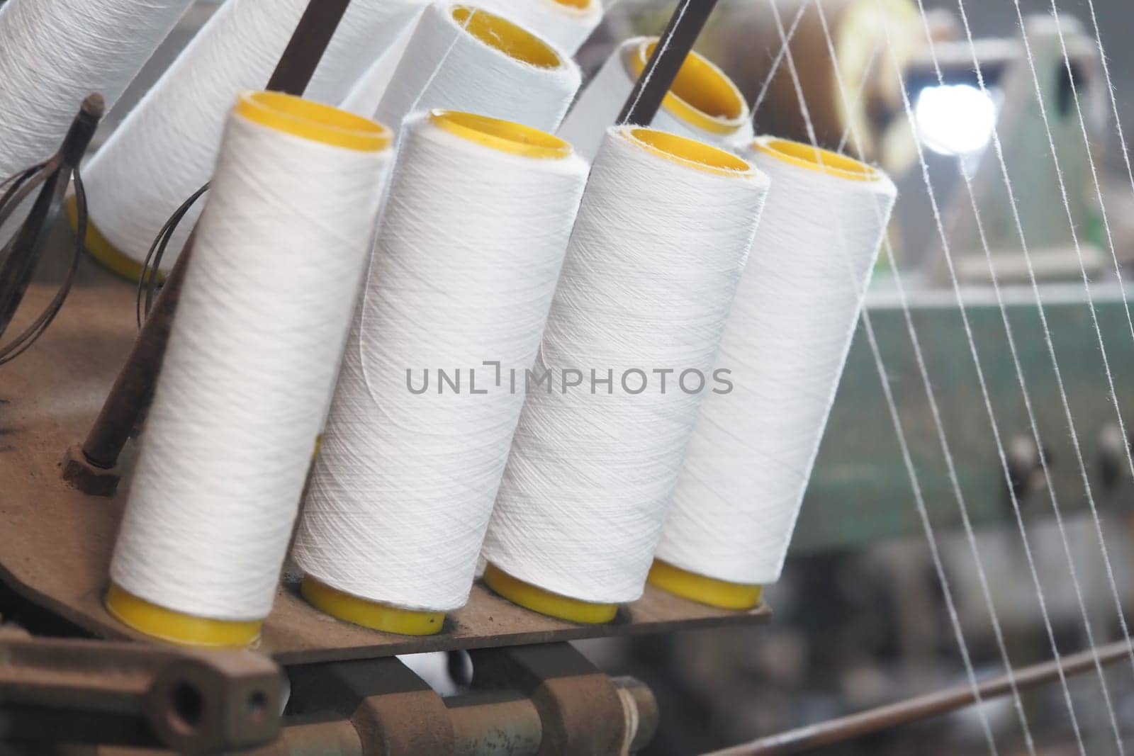 White thread spools on a textile machine highlight craftsmanship.