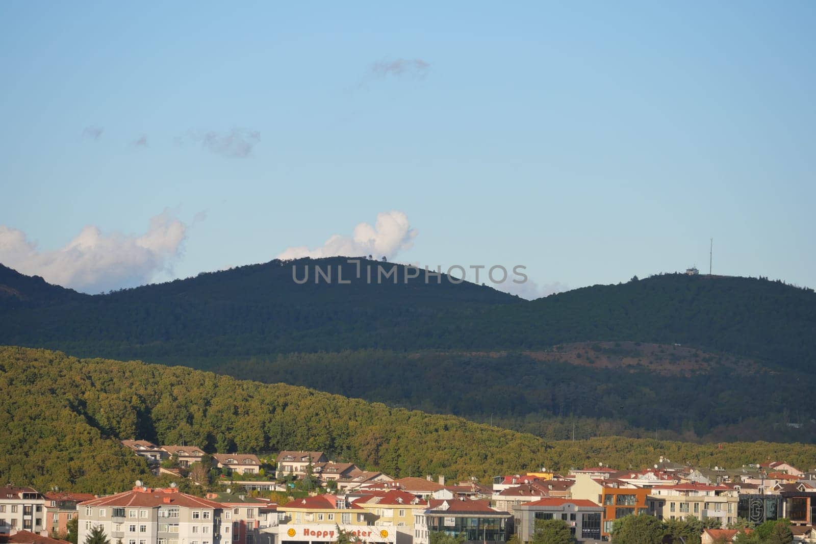 A view showcasing lush hills rising behind modern buildings under blue sky.