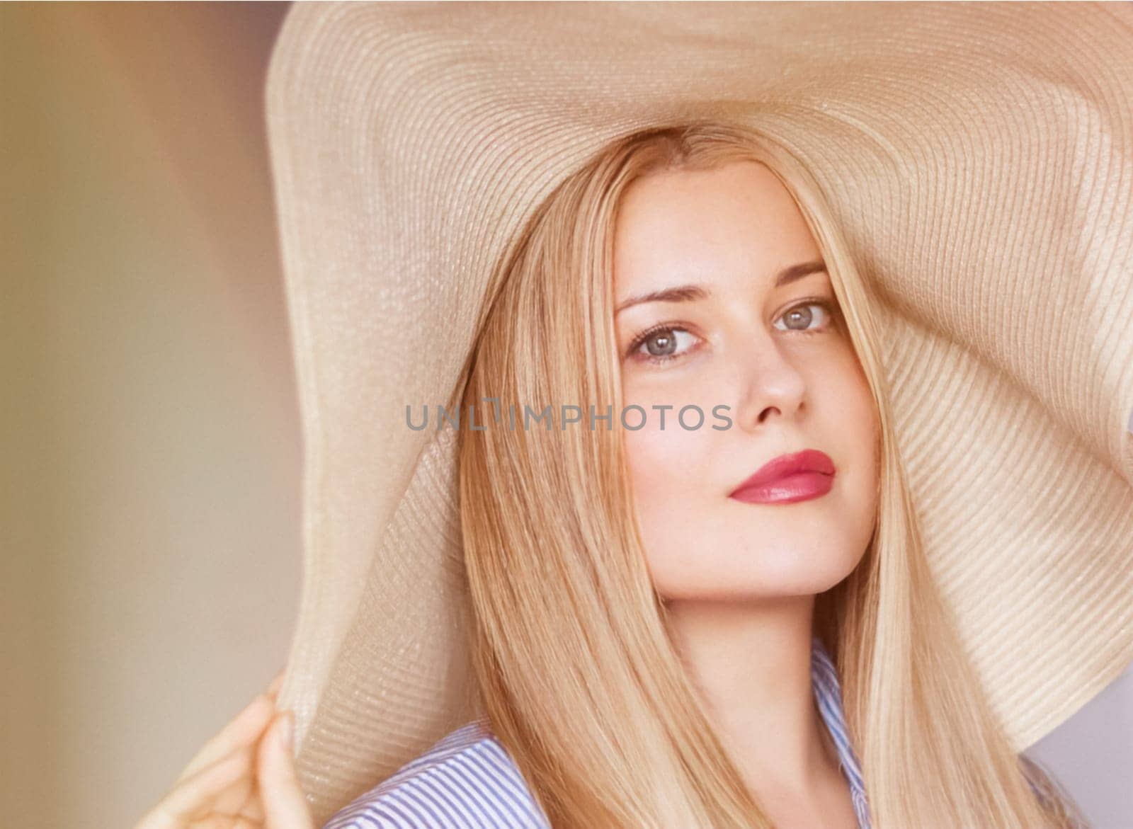 Woman, fashion and summer country charm, blonde beauty and elegance in wide brimmed beach hat. Feminine allure, timeless style and graceful glow. Smile, straw hat and blue striped blouse, natural lighting and effortless charm, fashion look idea