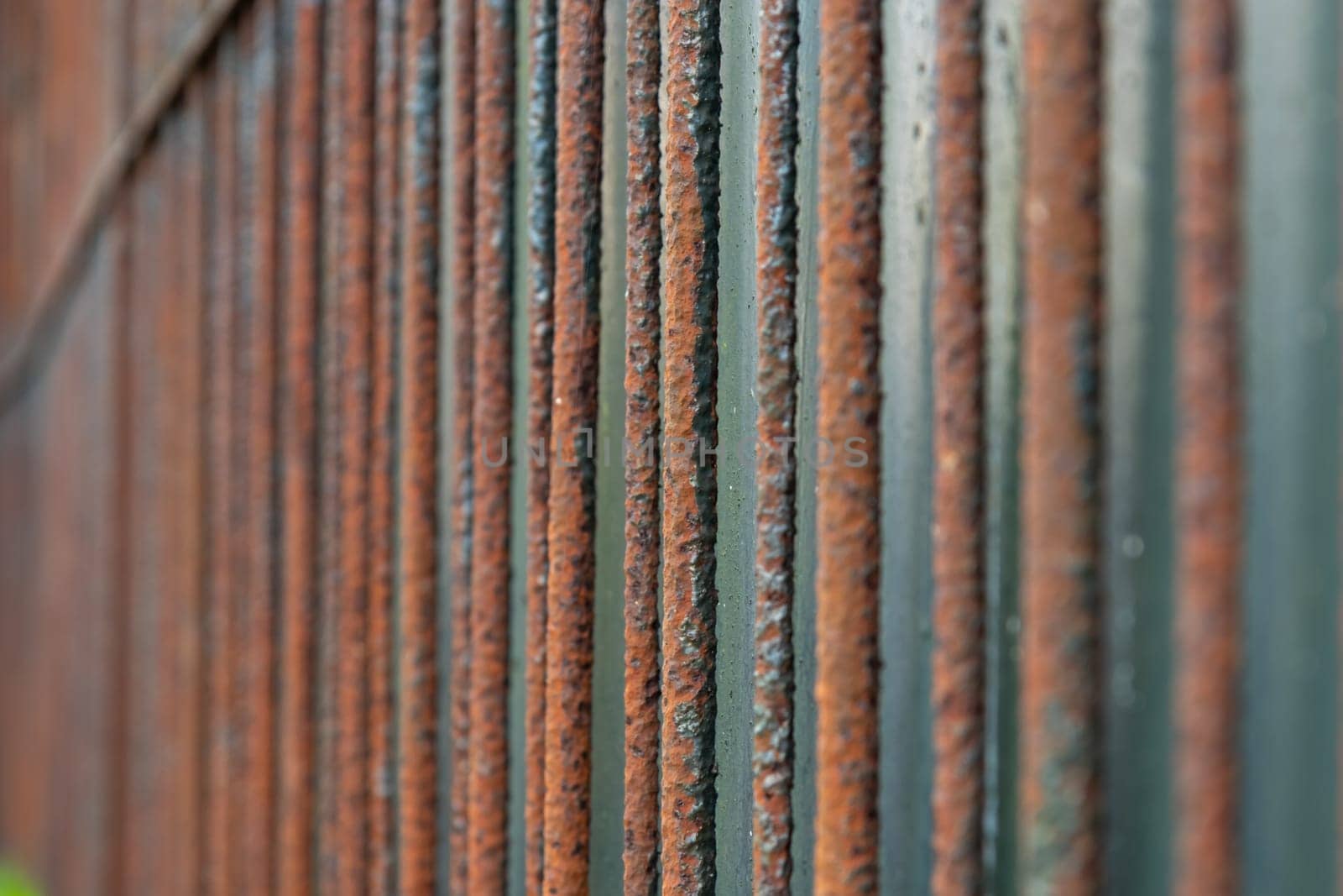 Rusty metal garden fence made of rods, close-up, abstract background .