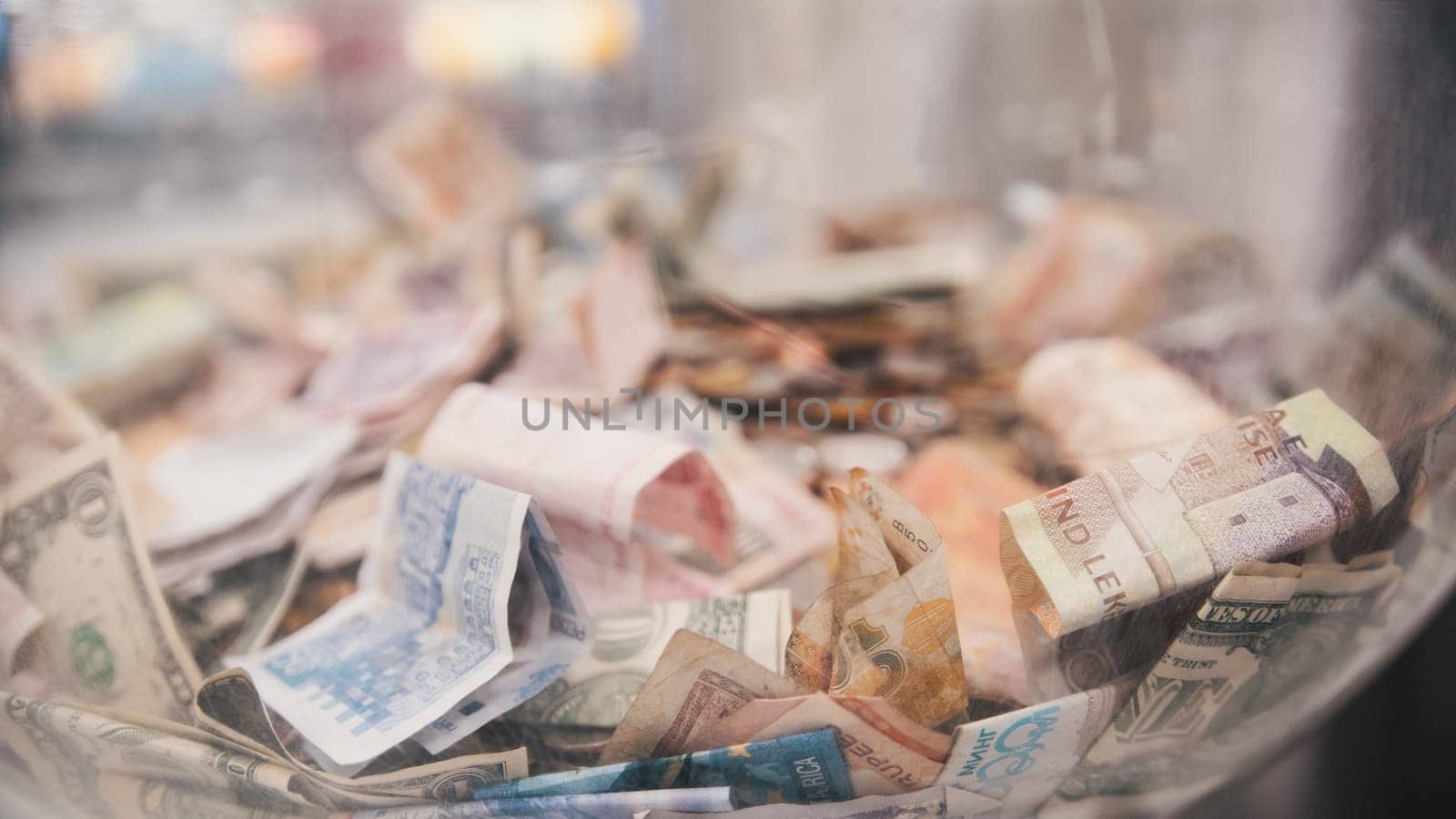 A lot of different bills - money of different countries in big glass jar, close up