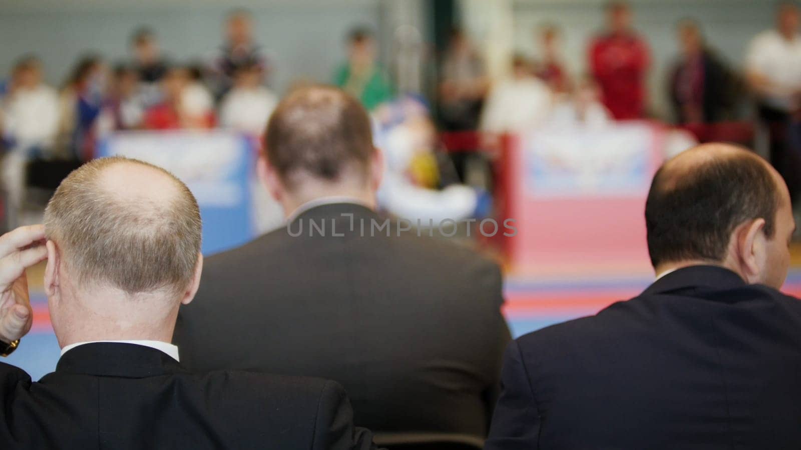 Martial art competitions - three bald men coaches looking at karate kid's fighting, close up
