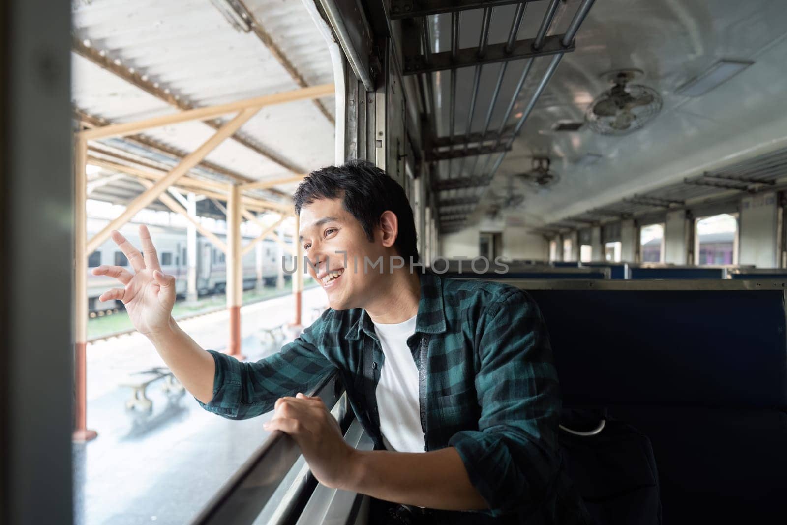 With a smile on his face, the young man watches the landscape pass by during his train ride, reflecting the joy and excitement of traveling.