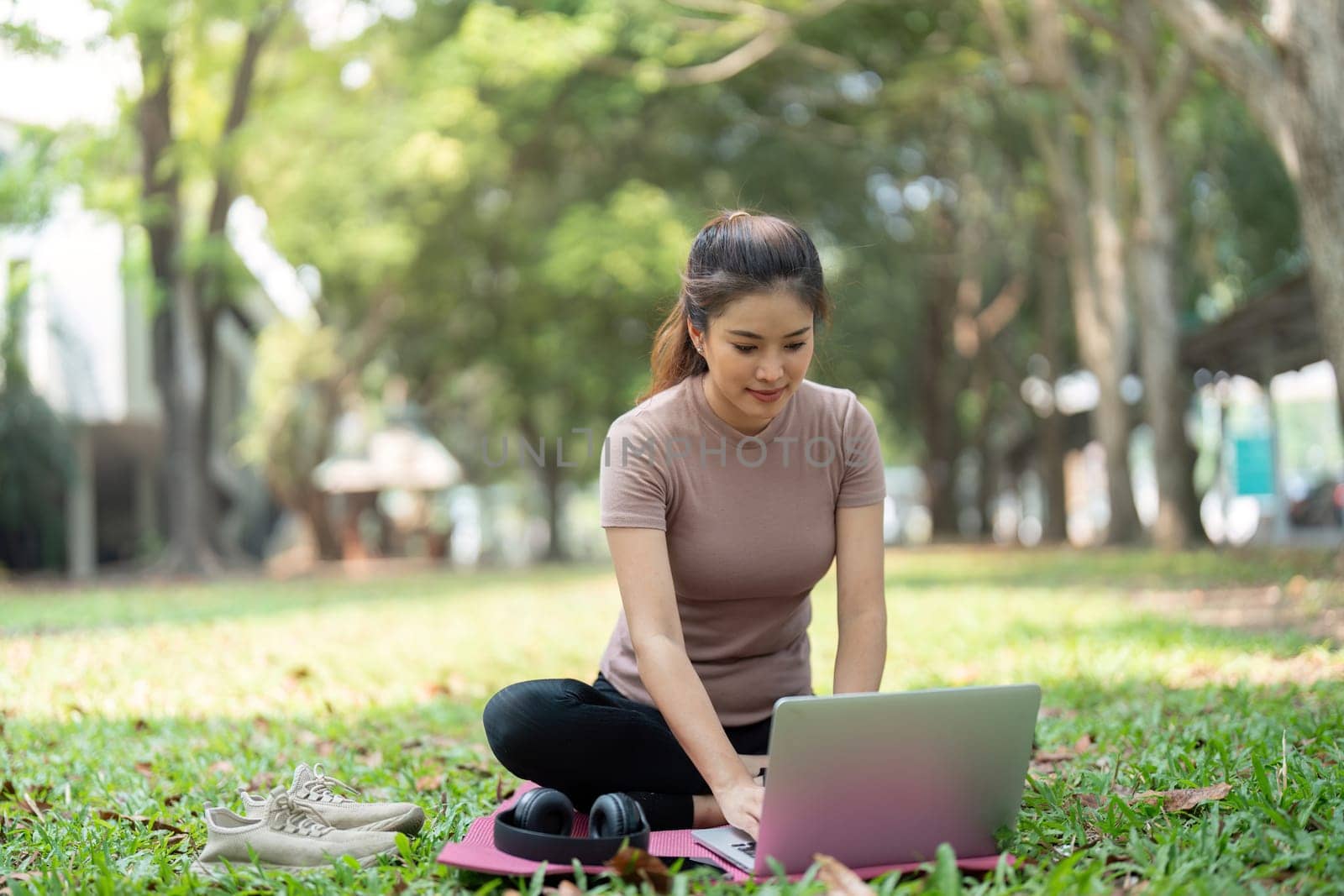 A modern depiction of work-life balance as a woman sits on a yoga mat, using her laptop in nature, blending productivity and wellness in her lifestyle.
