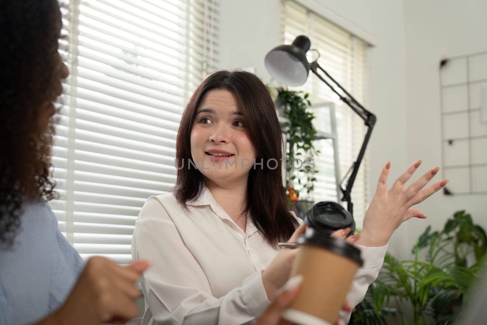 Two professionals exchange thoughts on projects accompanied by coffee, representing a friendly and collaborative atmosphere in a creative workspace.