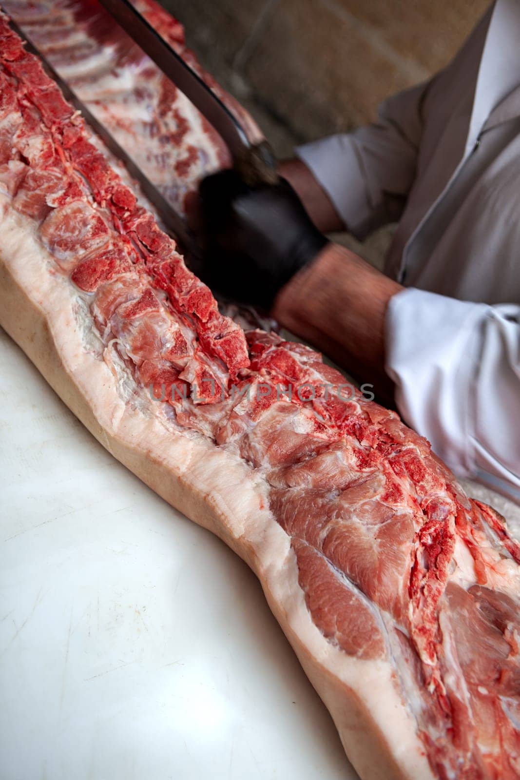 Butcher cutting a pork with a saw