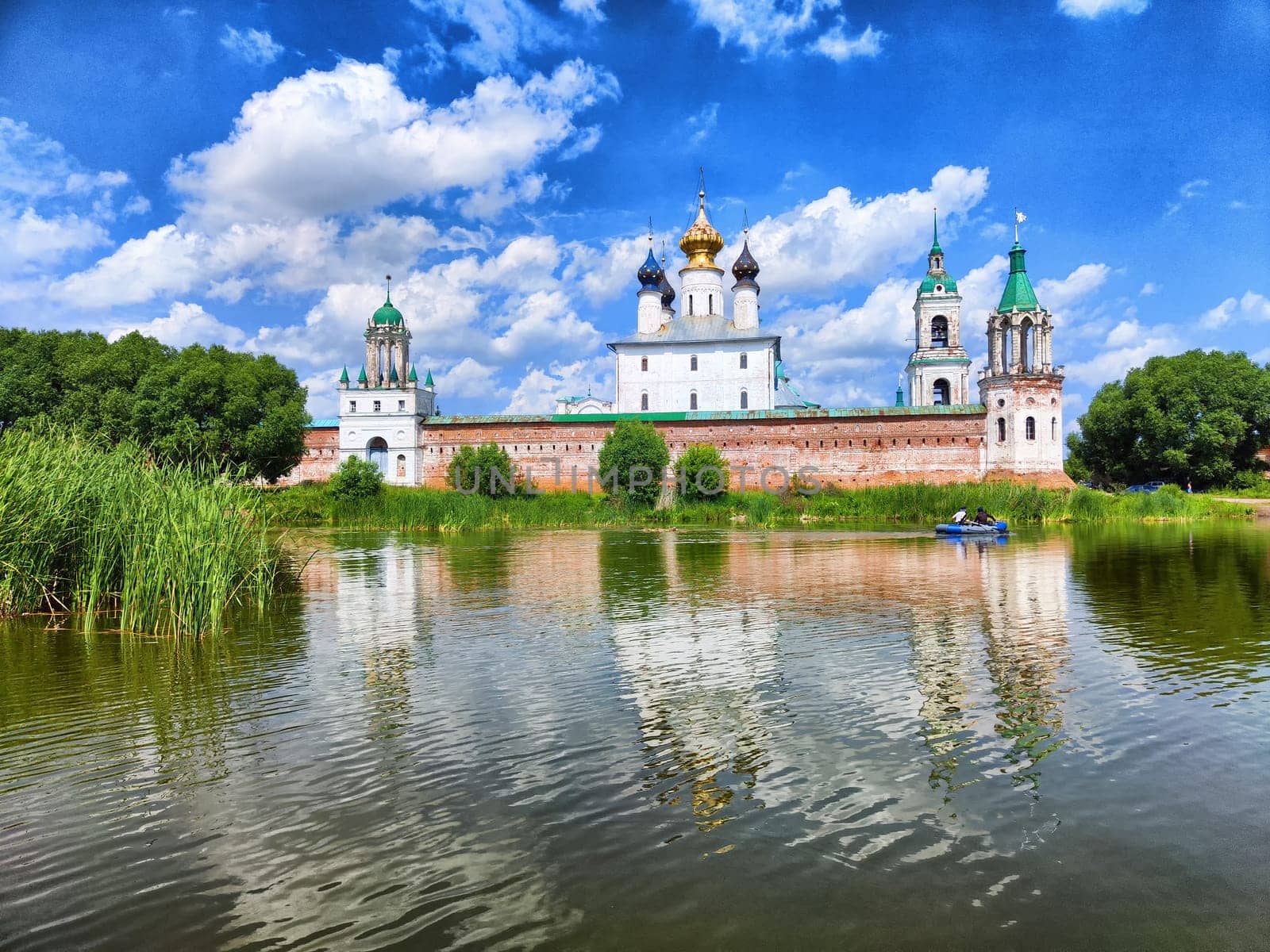 The Kremlin in Rostov the Great showcases stunning architecture reflected in calm waters under a vibrant sky, attracting visitors and locals alike.