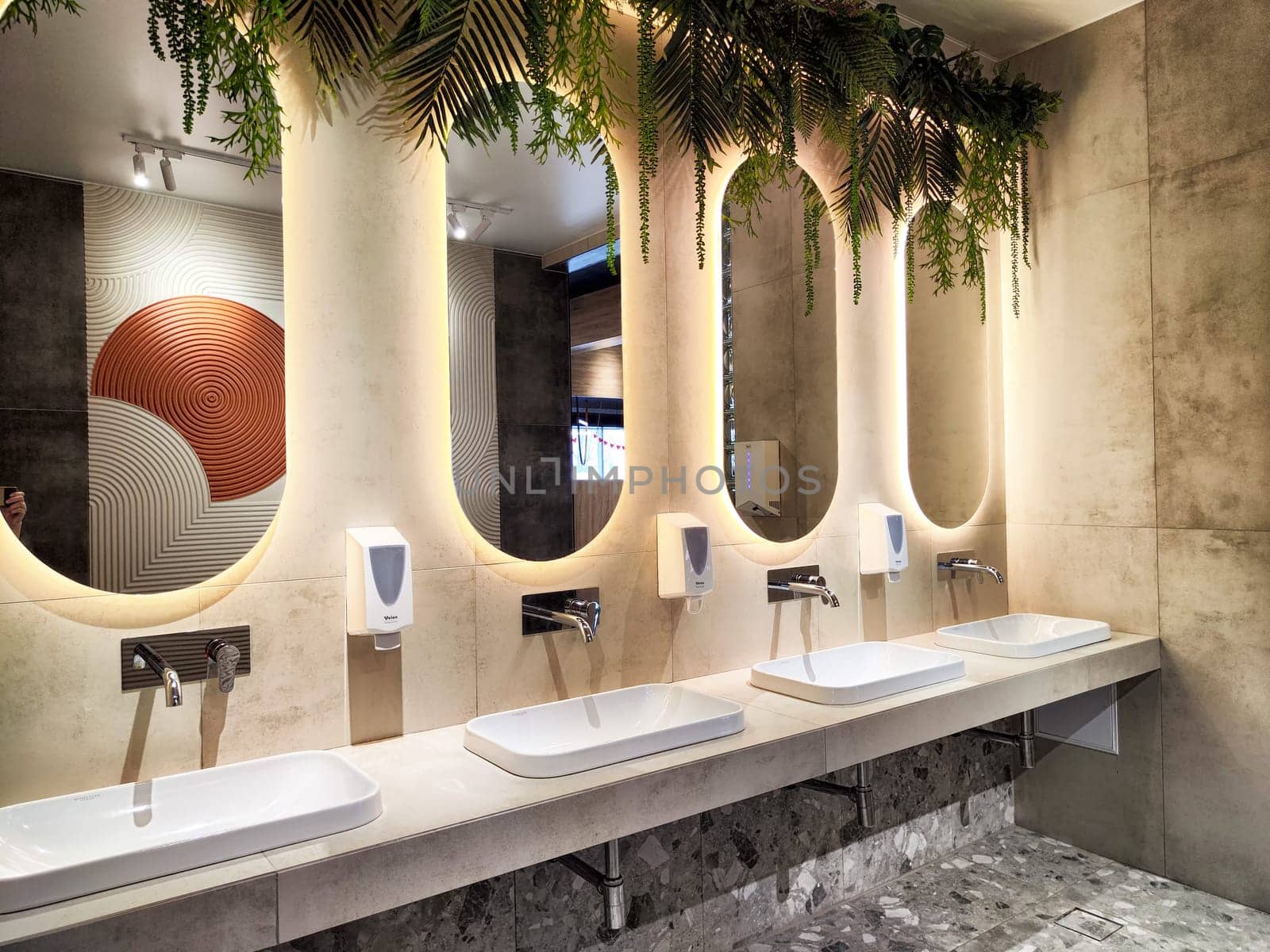 A contemporary restroom showcases elegant sinks under warm lighting, designed with natural elements for a relaxing atmosphere.