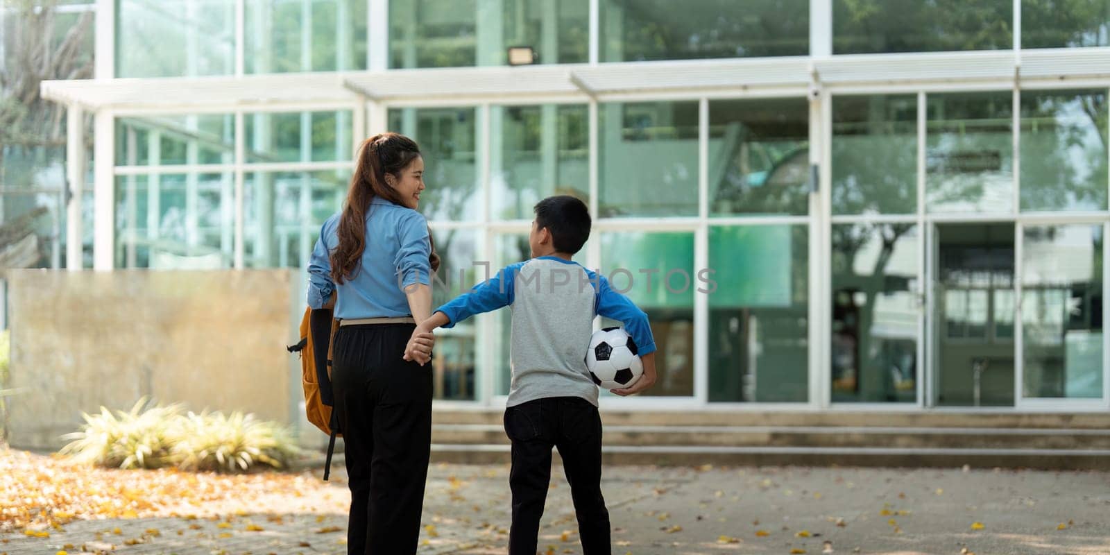The young boy waves goodbye to his mother with a smile, ready for his school day. Their interaction reflects a loving family bond.