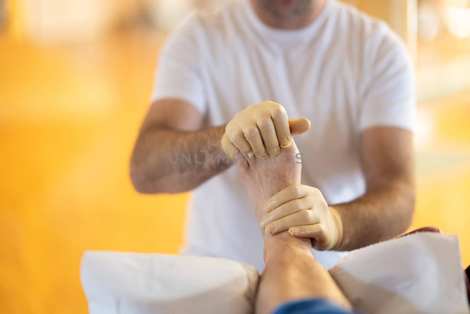 A physiotherapist treating a patients foot in a busy rehabilitation center, focusing on recovery and mobility improvement.