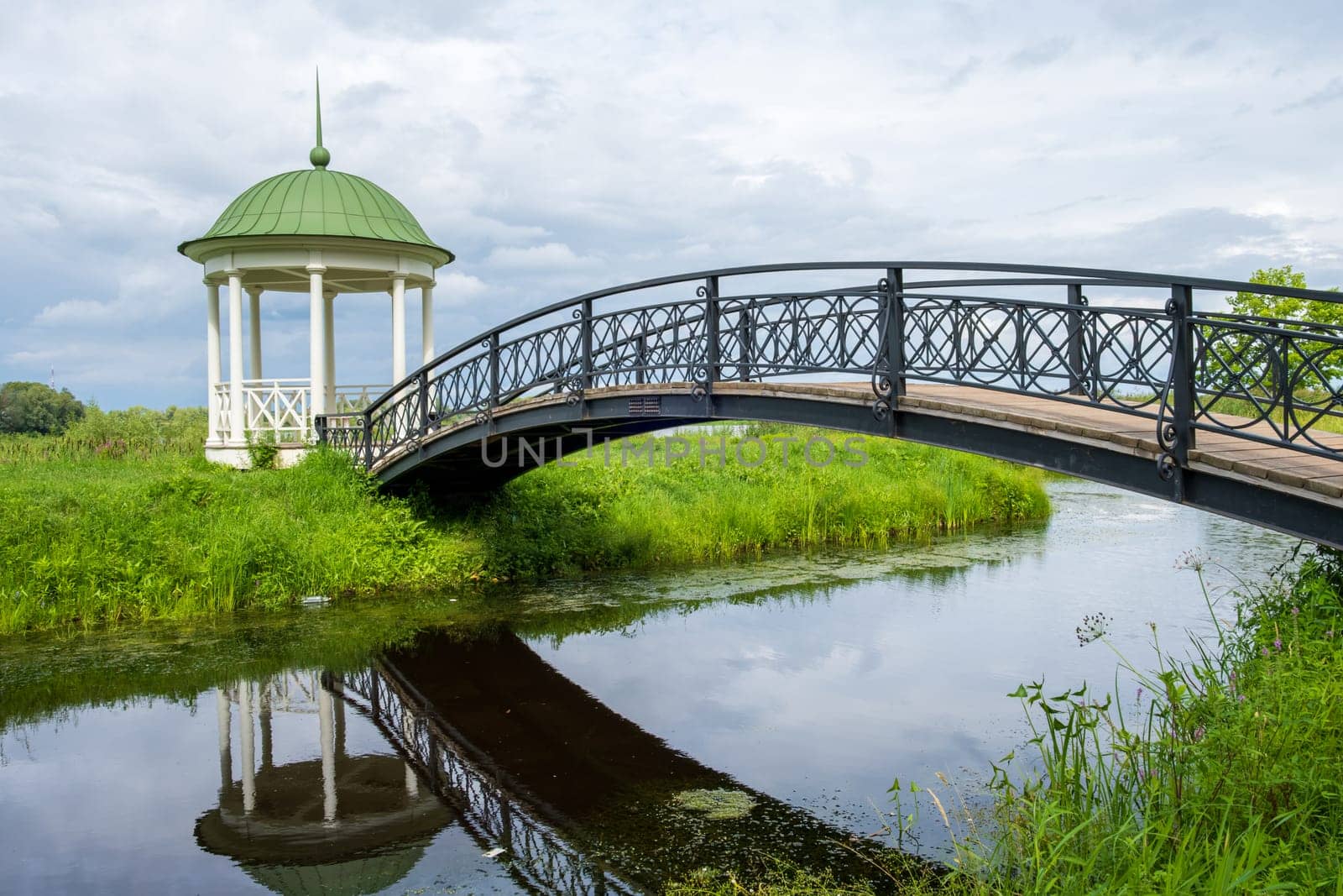 Veliky Novgorod, Russia - 07.30.24. Anna's gazebo and an elegant arched bridge over the channel. Vitoslavlitsy Museum-Reserve.