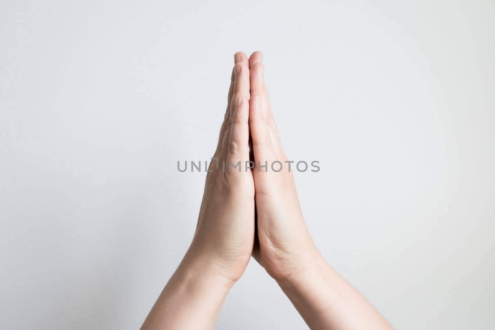 Close up of caucasian adult hands in prayer gesture against white background.