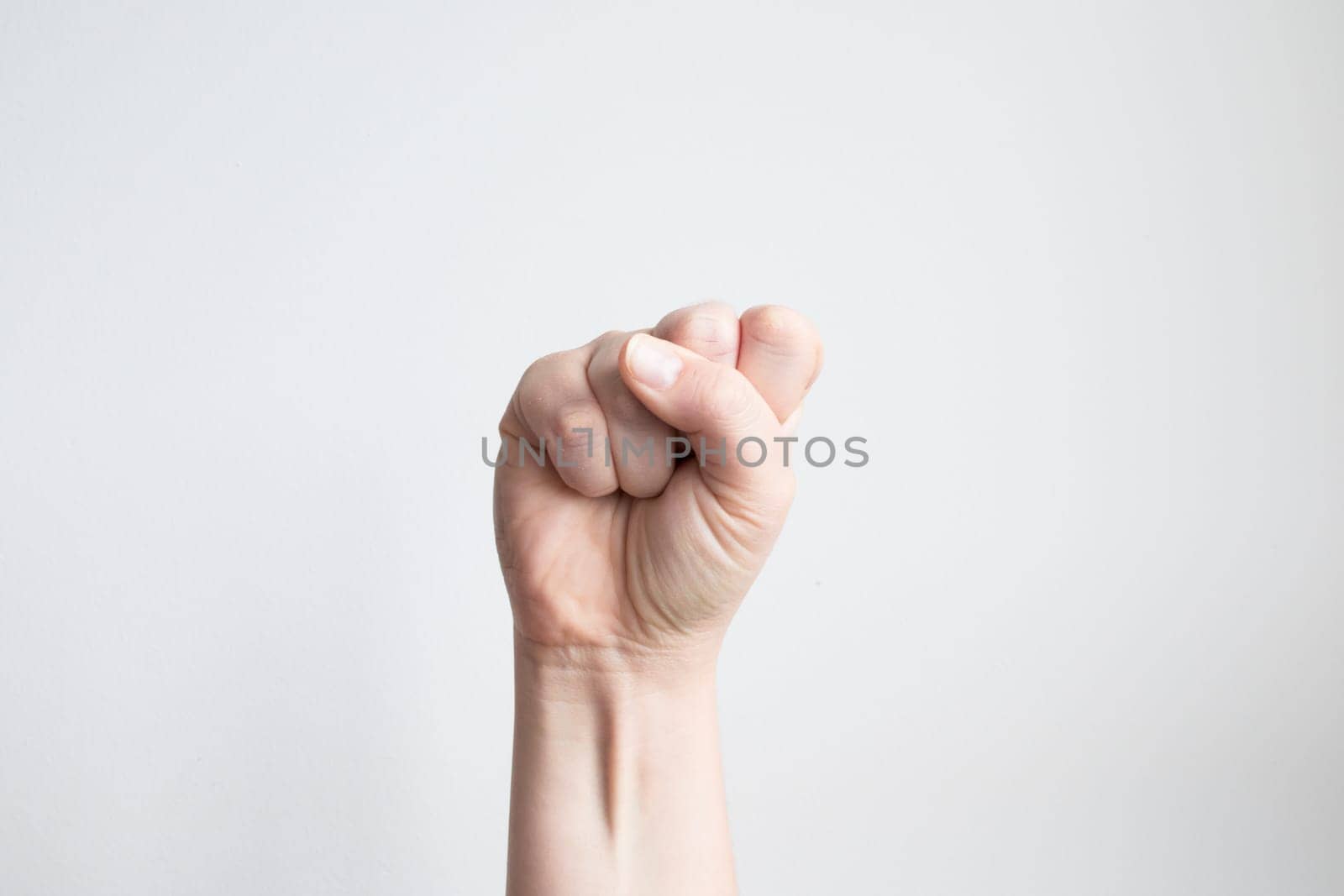 Caucasian female hand fist gesture against white background.