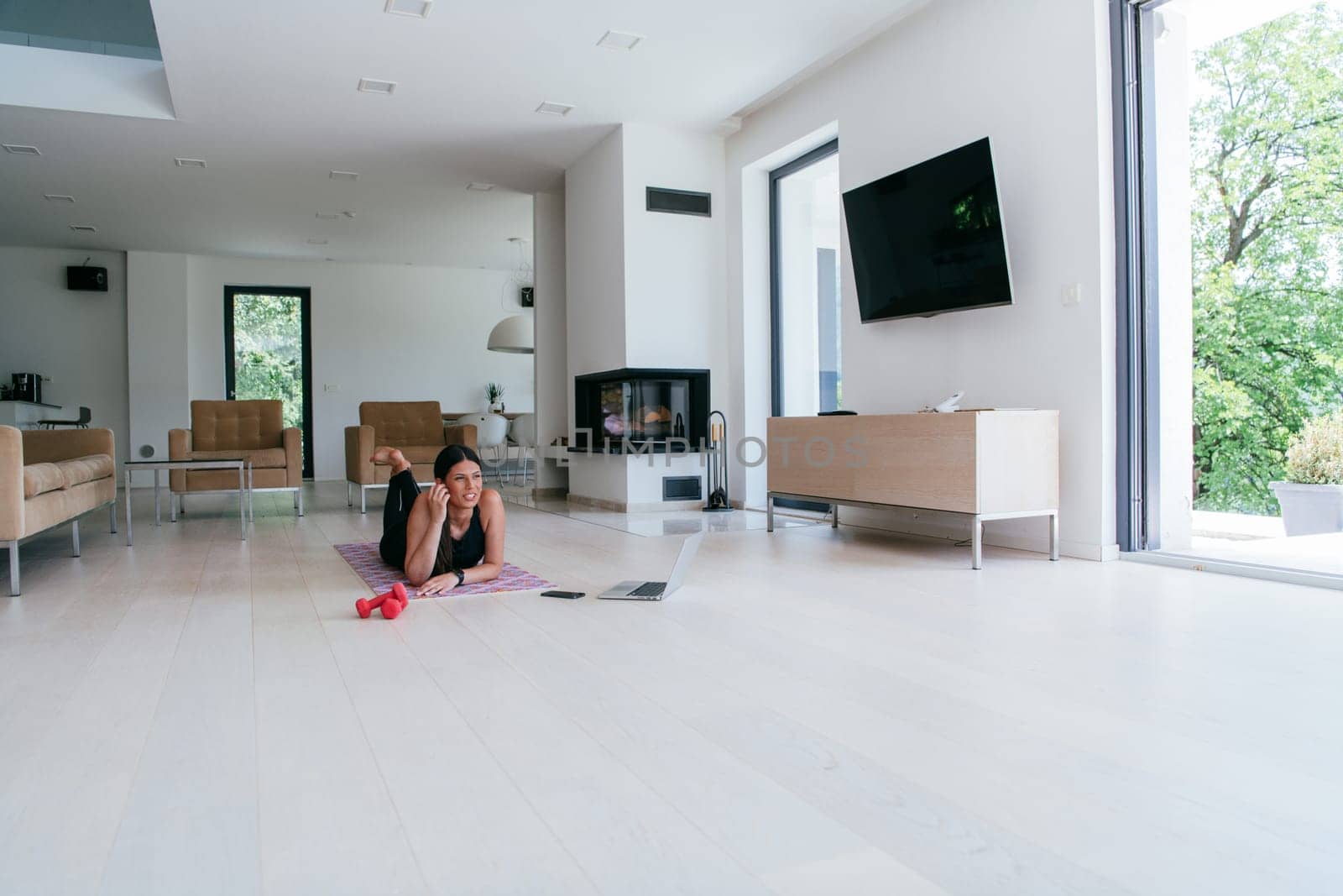Young woman resting after online training while lying on the living room floor