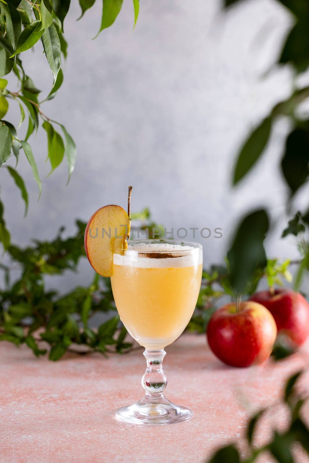 Apple cider cocktail in elegant glass, garnished with fresh apple slice and a sprinkle of cinnamon, creating a tempting autumn beverage