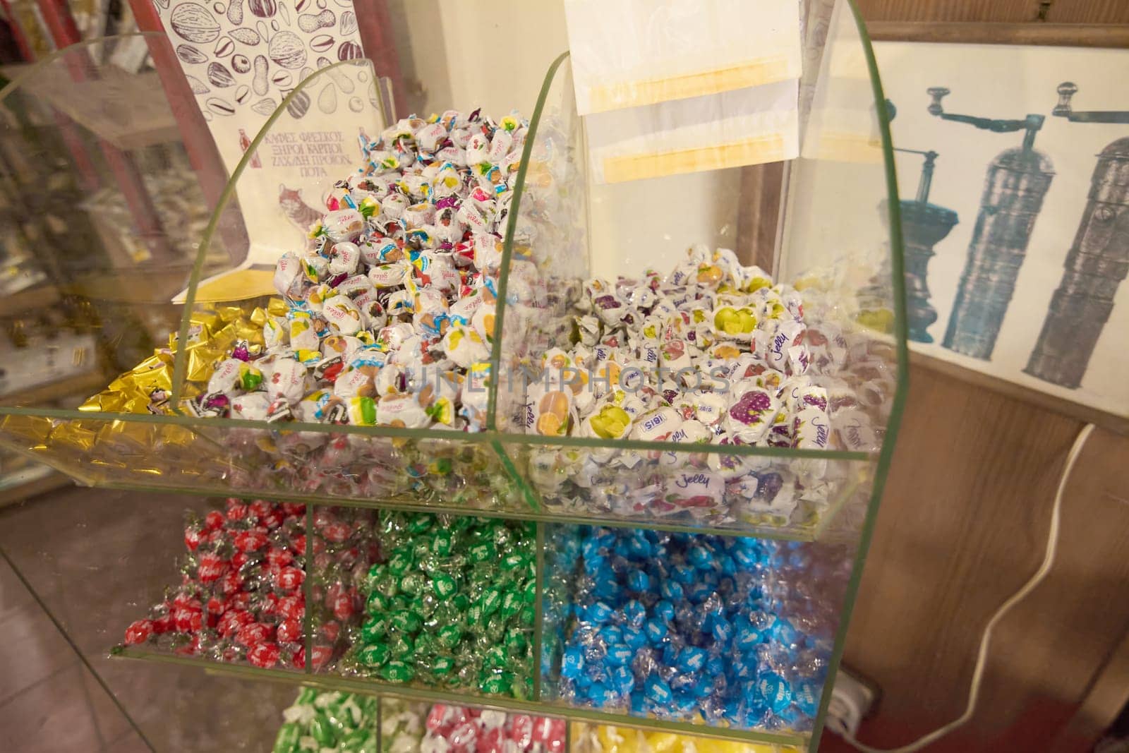 Crete.Greece - april 02, 2025: Colorful candies with playful wrappers in glass containers, organized by type and color, showcasing a bright and cheerful assortment in a shop setting.