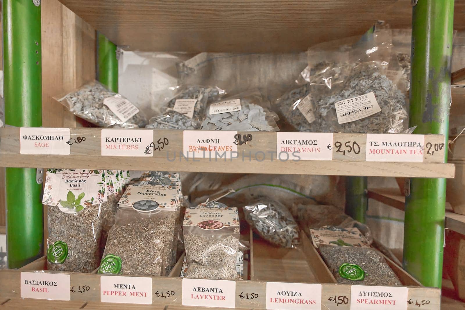 Crete.Greece - april 02, 2025: Herb packets with Greek and English labels including sage, bay leaves, and mountain tea, neatly arranged on wooden shelves in a rustic shop interior.
