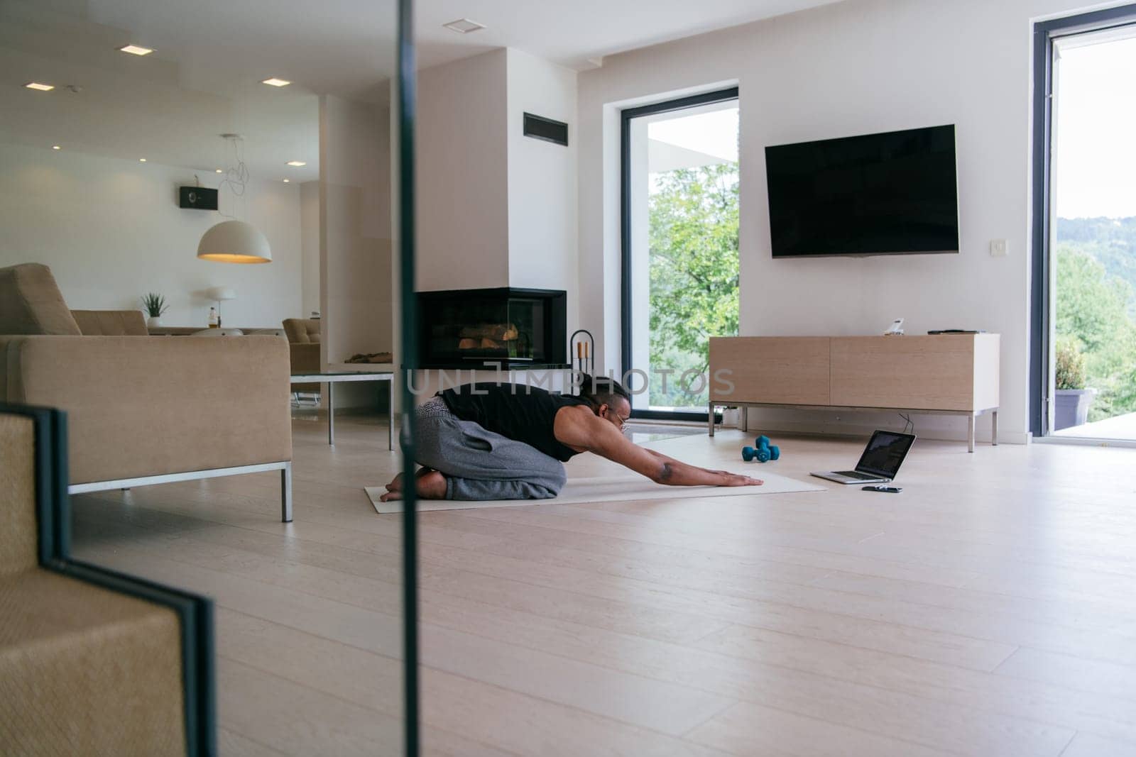 Training At Home. Sporty African American man doing the training while watching an online tutorial on a laptop, exercising in the living room, free space.