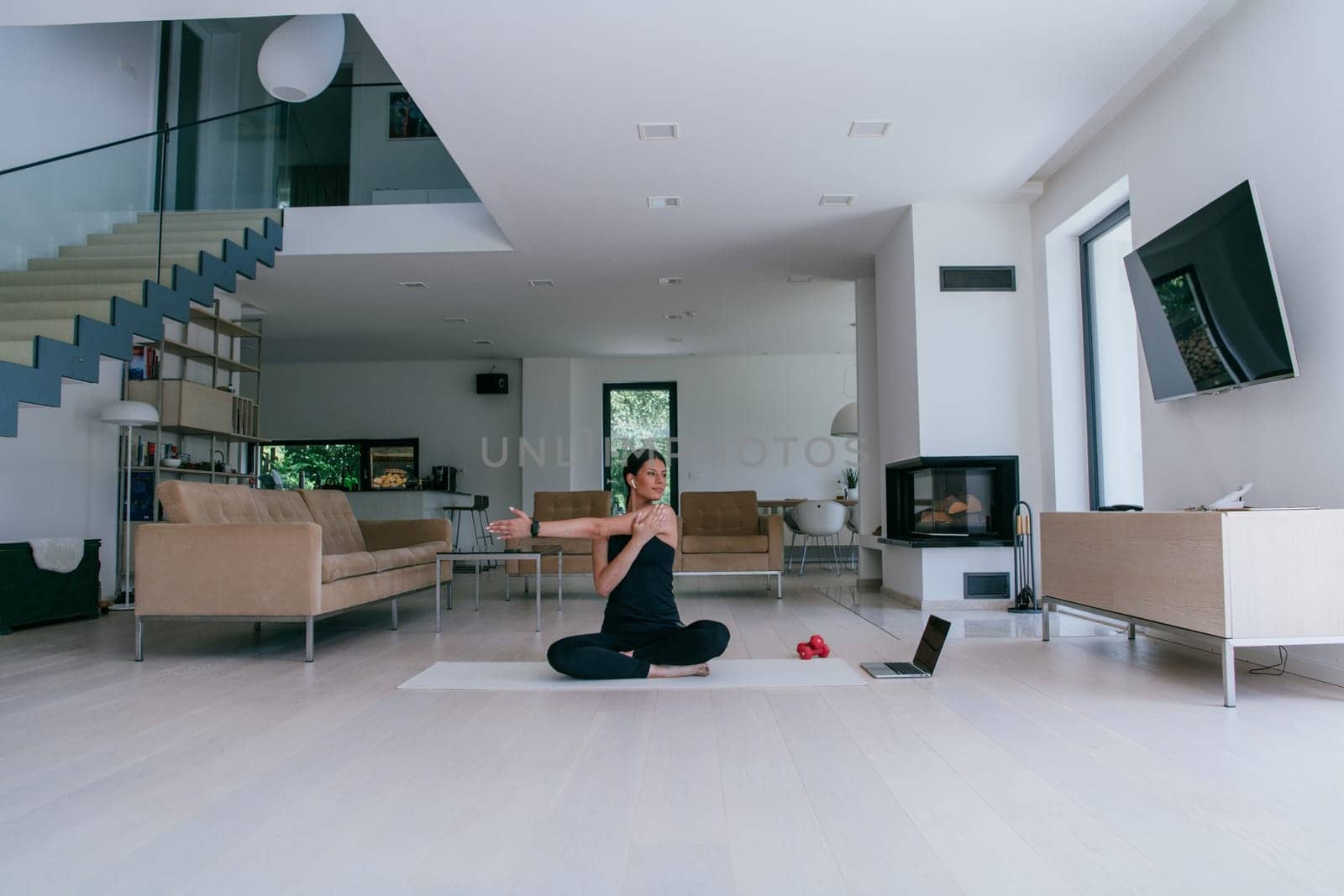 Young Beautiful Female Exercising, Stretching and Practising Yoga with Trainer via Video Call Conference in Bright Sunny House. Healthy Lifestyle, Wellbeing and Mindfulness Concept.
