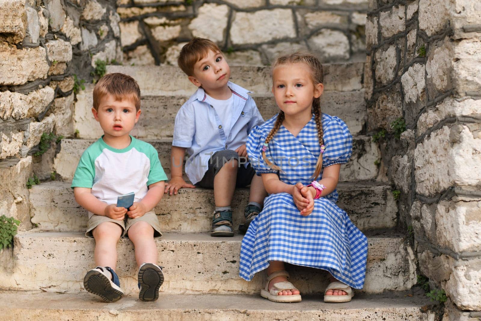 Children friends brothers and sister on the steps in the park