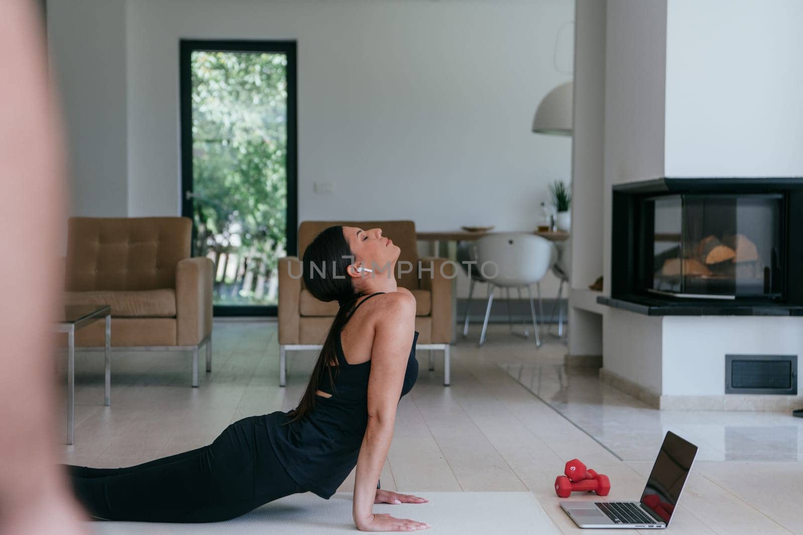 Young Beautiful Female Exercising, Stretching and Practising Yoga with Trainer via Video Call Conference in Bright Sunny House. Healthy Lifestyle, Wellbeing and Mindfulness Concept.