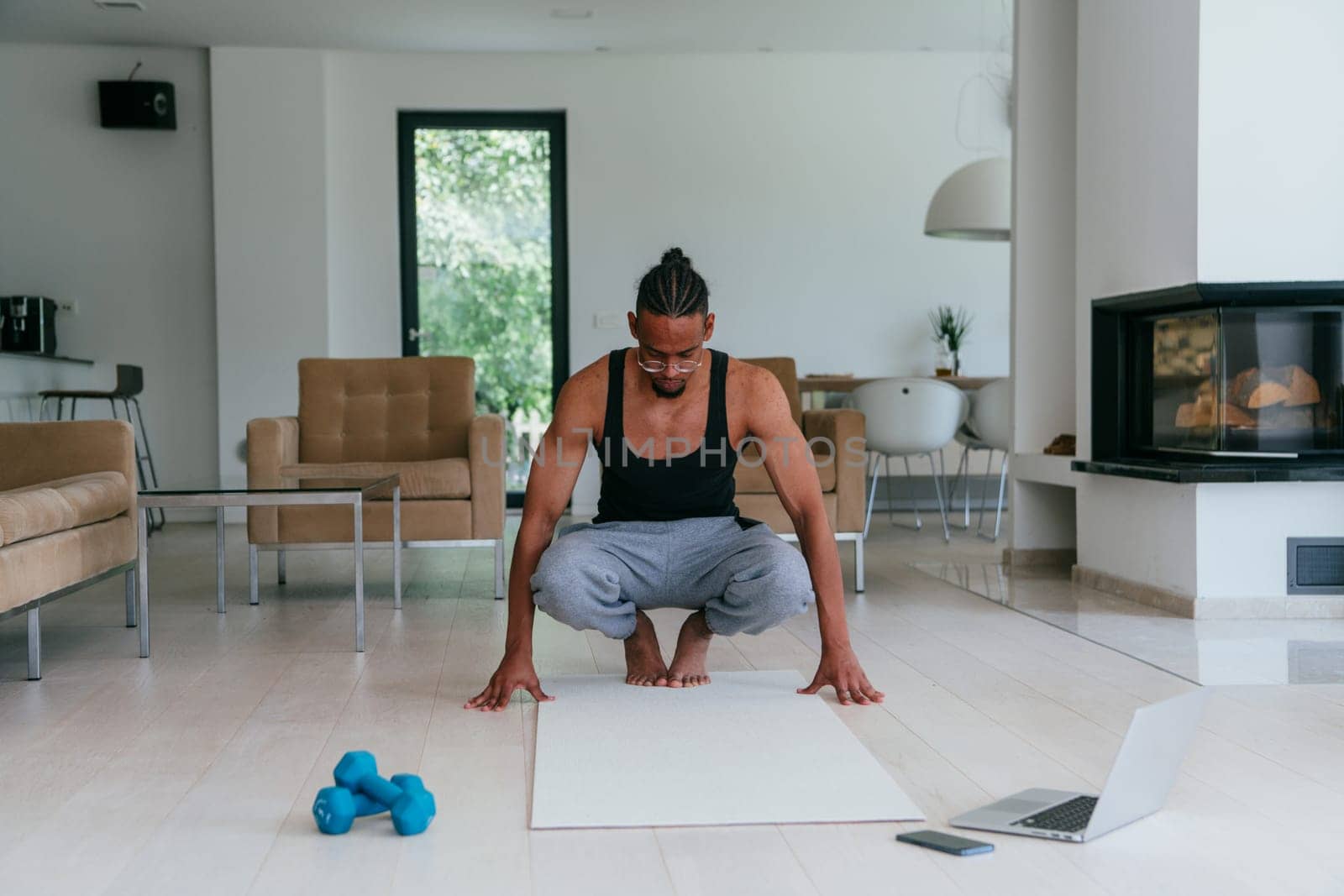Training At Home. Sporty African American man doing the training while watching an online tutorial on a laptop, exercising in the living room, free space.