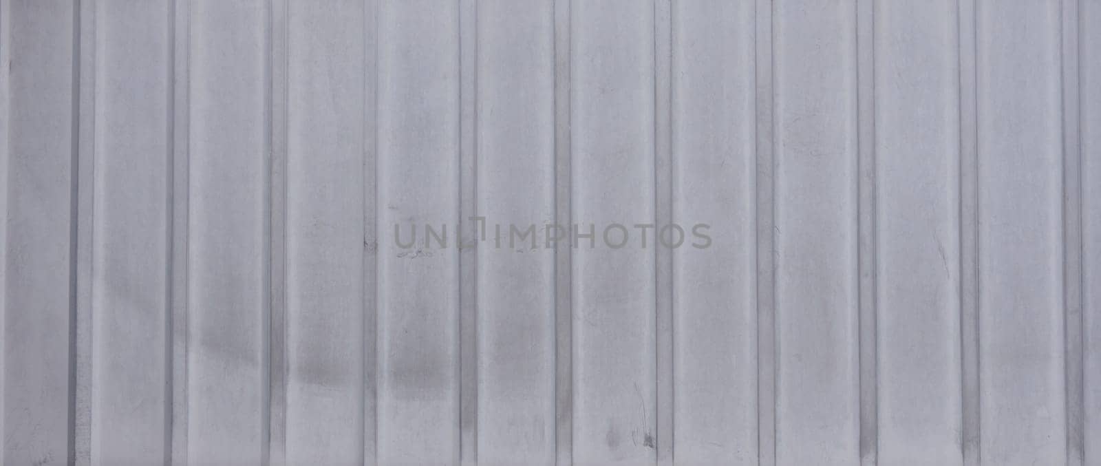 Gray metal siding texture with vertical lines. The siding has a matte finish and a slightly weathered appearance