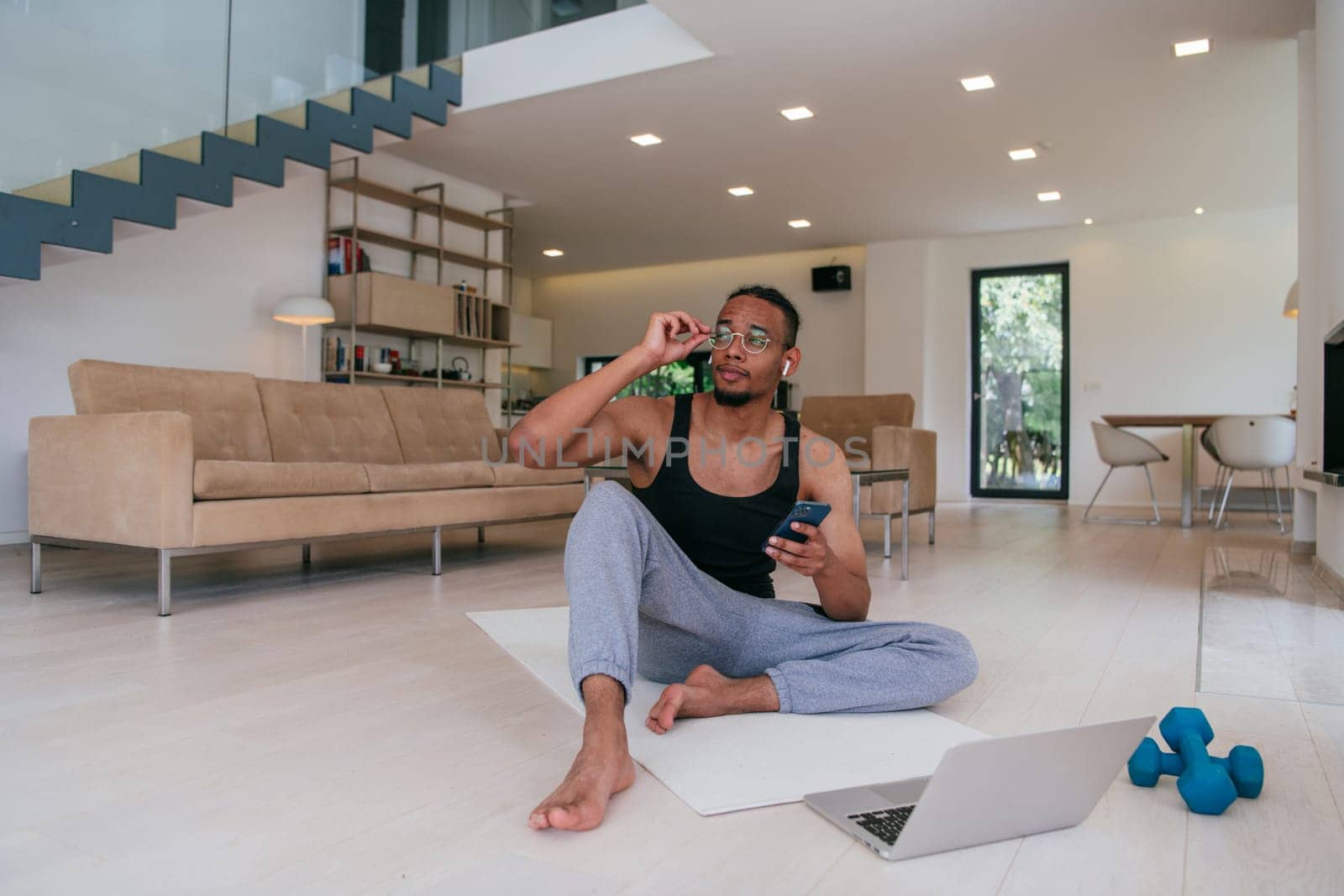 Training At Home. Sporty man doing the training while watching an online tutorial on a laptop, exercising in the living room, free space
