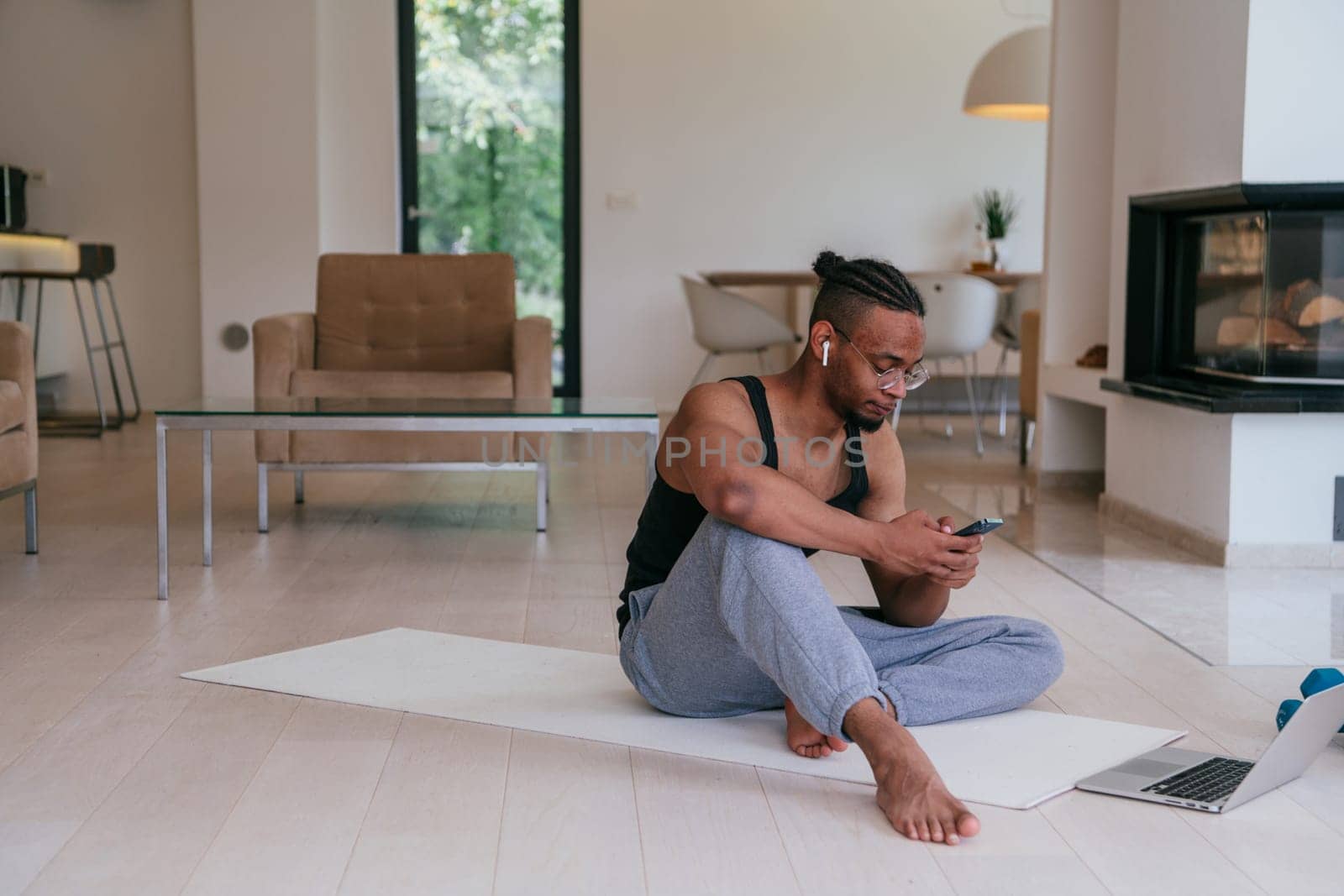 Training At Home. Sporty man doing the training while watching an online tutorial on a laptop, exercising in the living room, free space