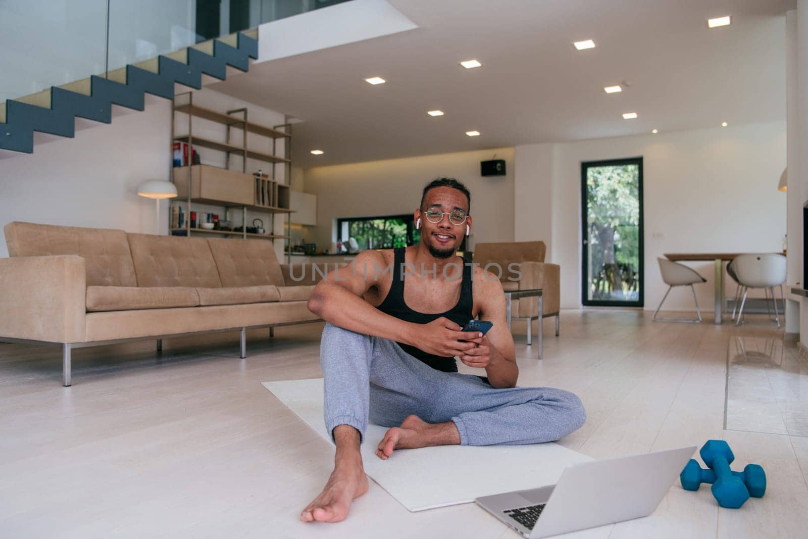 Training At Home. Sporty man doing the training while watching an online tutorial on a laptop, exercising in the living room, free space