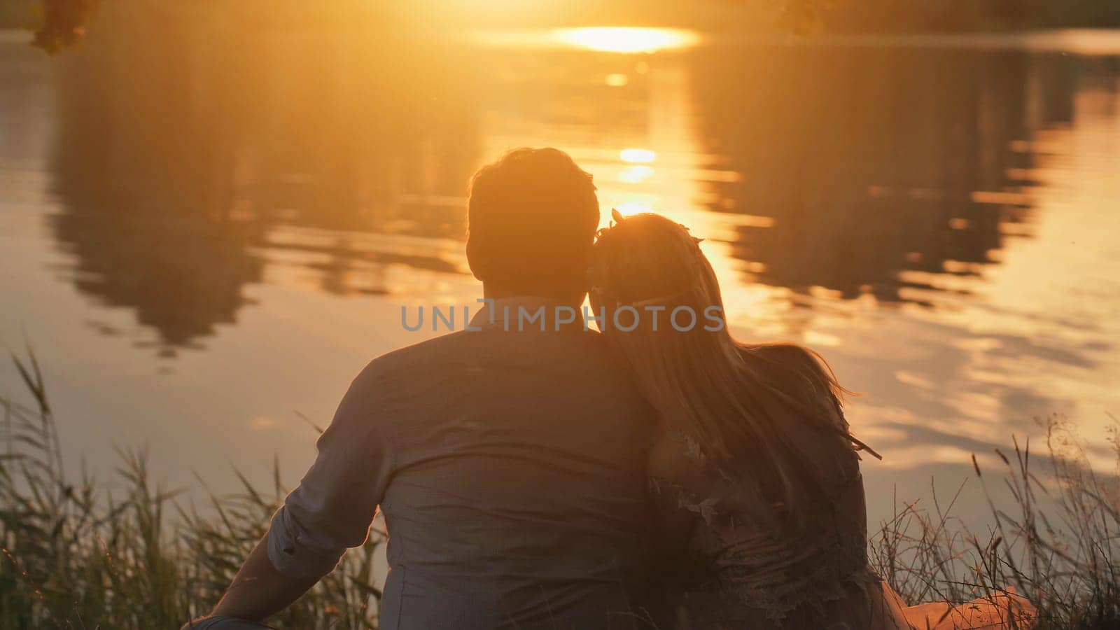 A young couple sits on a lake at sunset