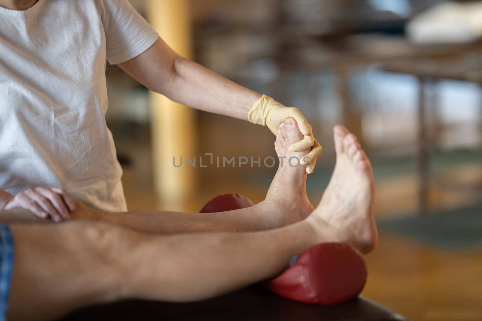 A physiotherapist treating a patients foot in a busy rehabilitation center, focusing on recovery and mobility improvement.