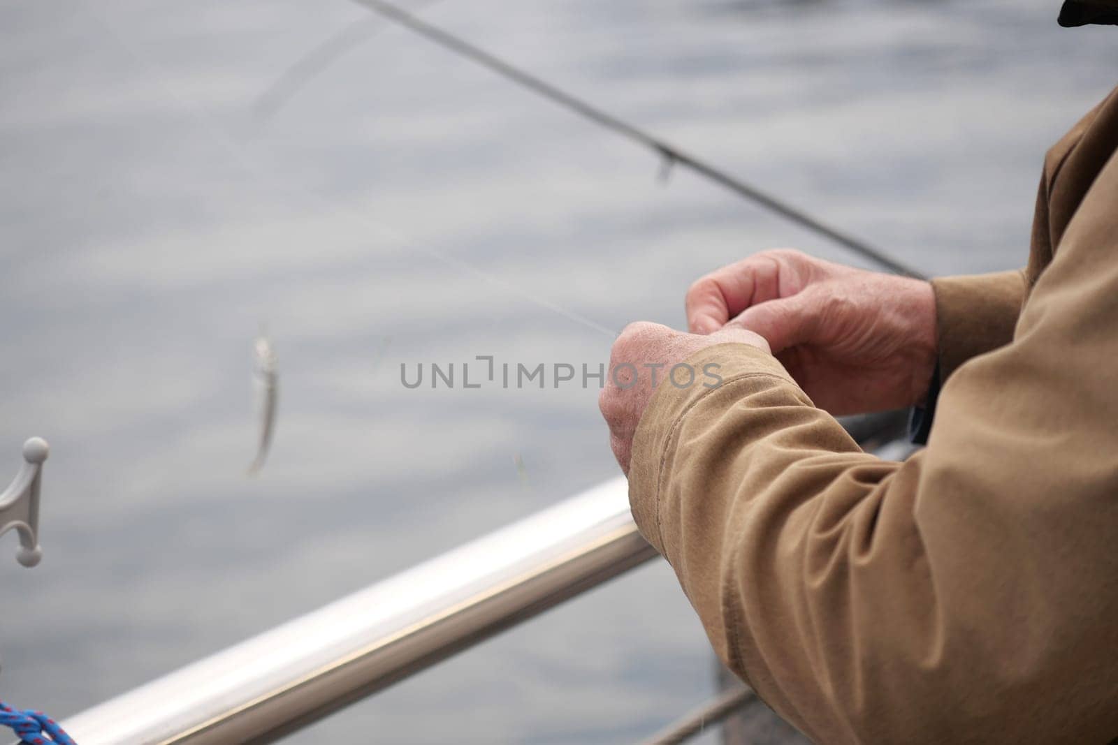 A person expertly ties fishing tackle on a boat during early morning.