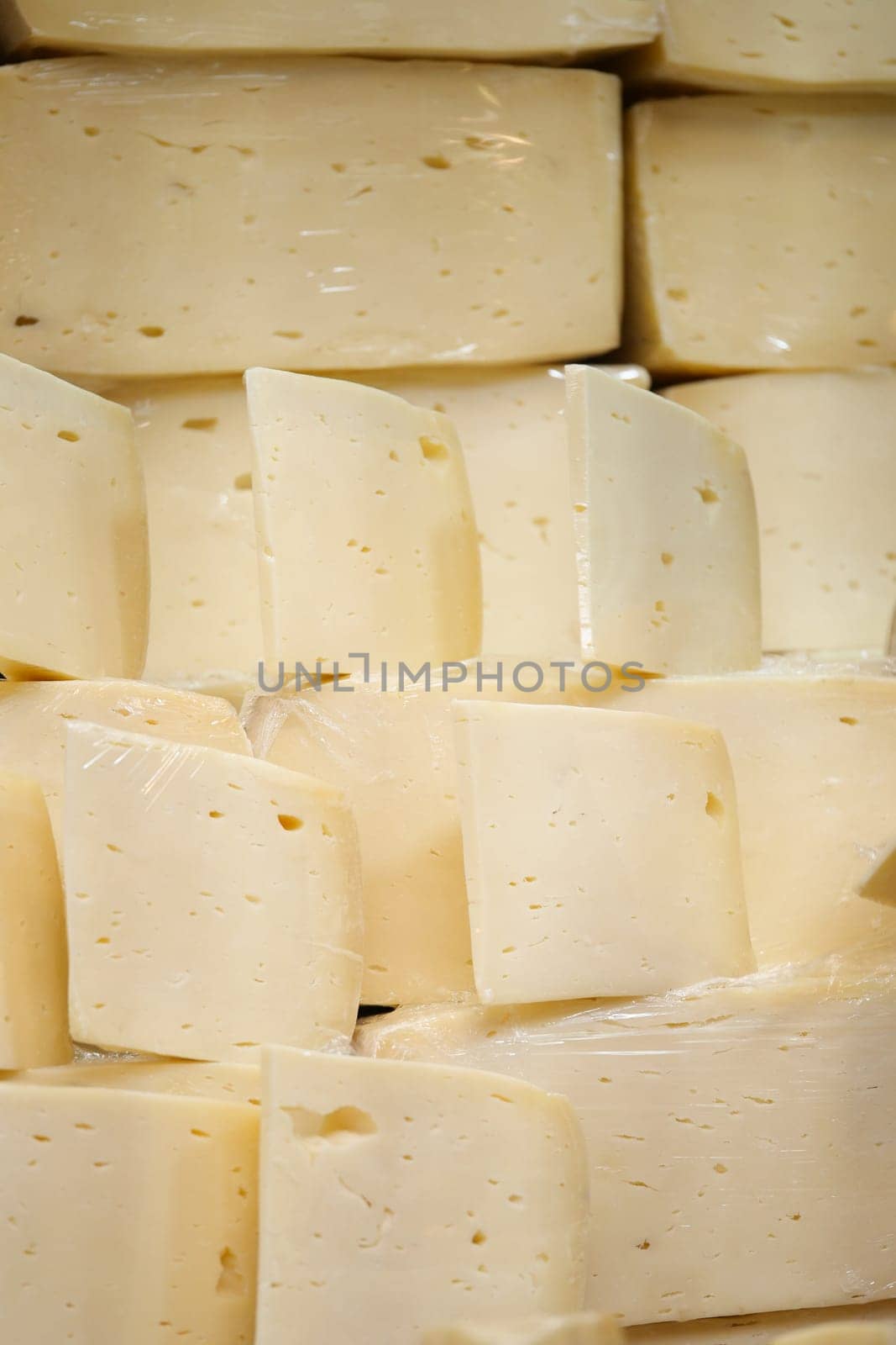Various blocks of fresh cheese are neatly arranged in a market display.
