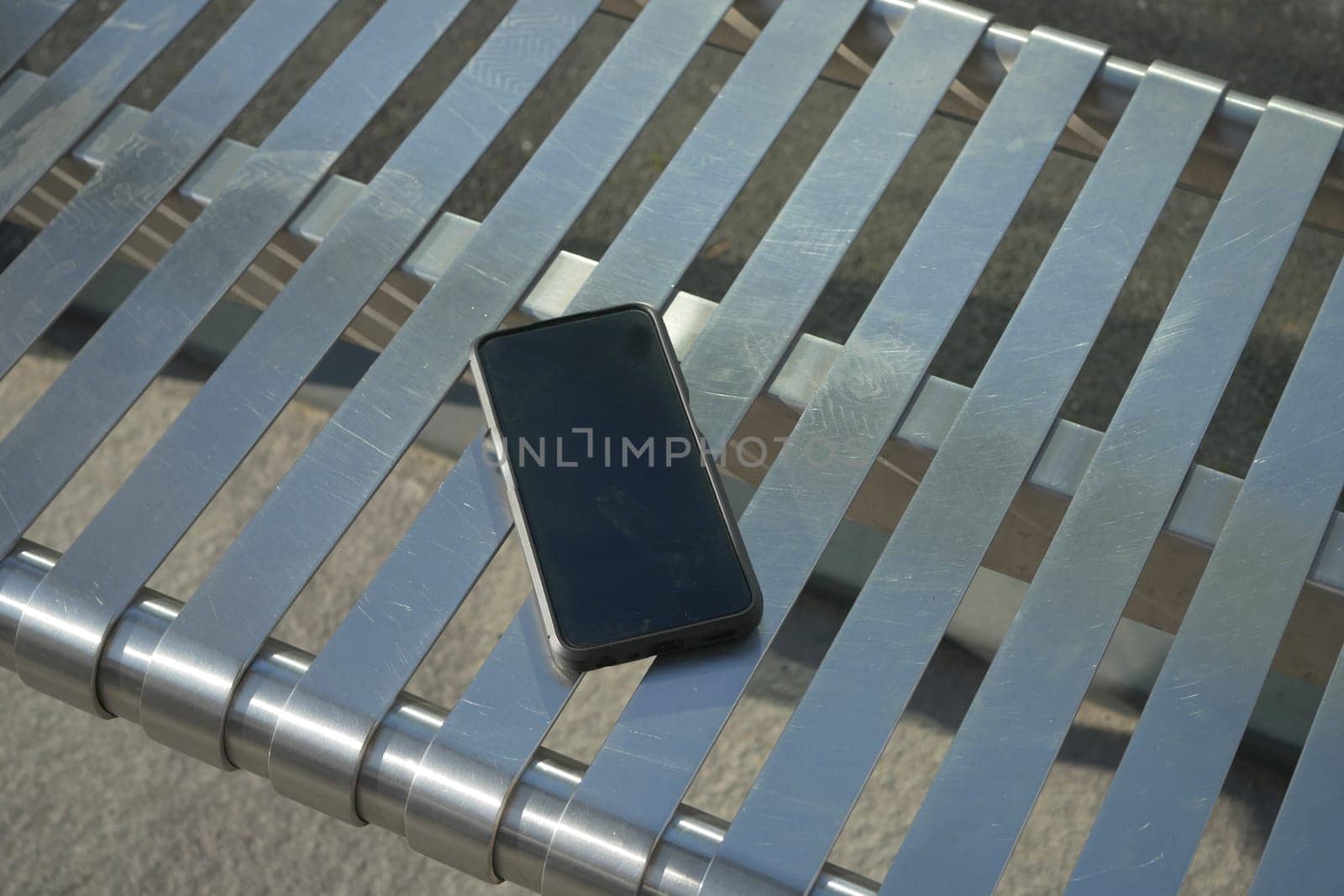 lost Smartphone rests on metallic bench ,