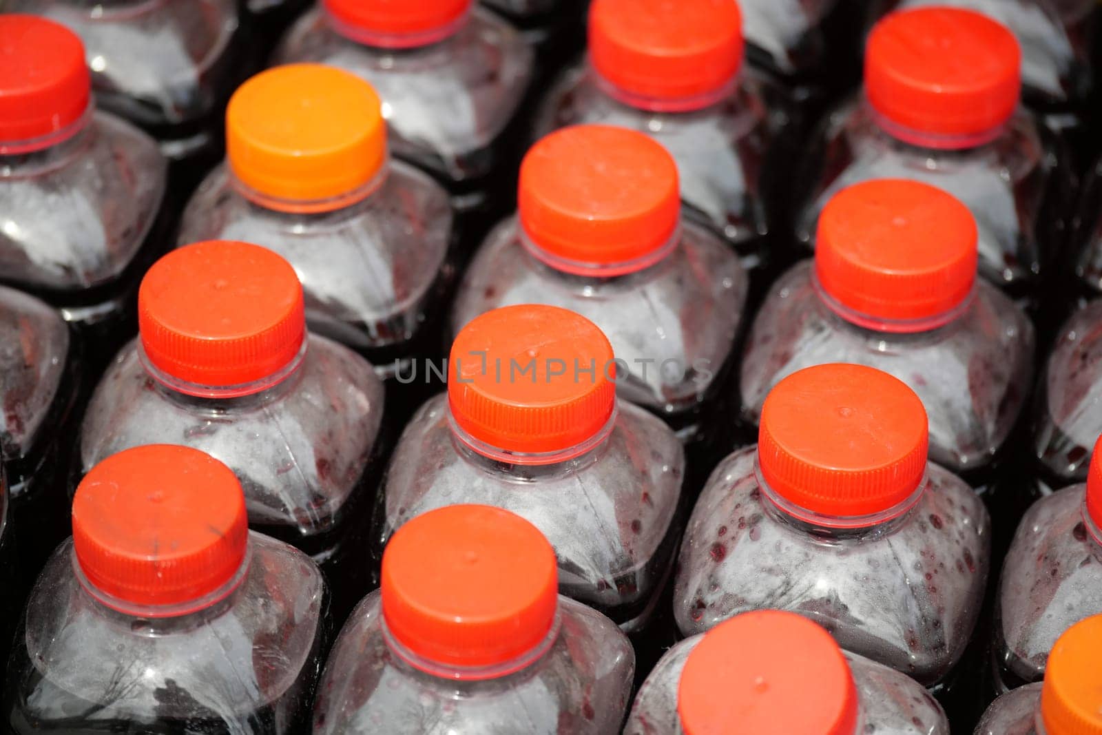 Numerous bottles with orange caps are arranged orderly for sale.