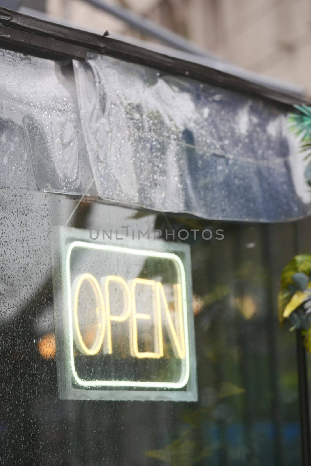 Raindrops cling to the window as a bright sign beckons visitors inside.