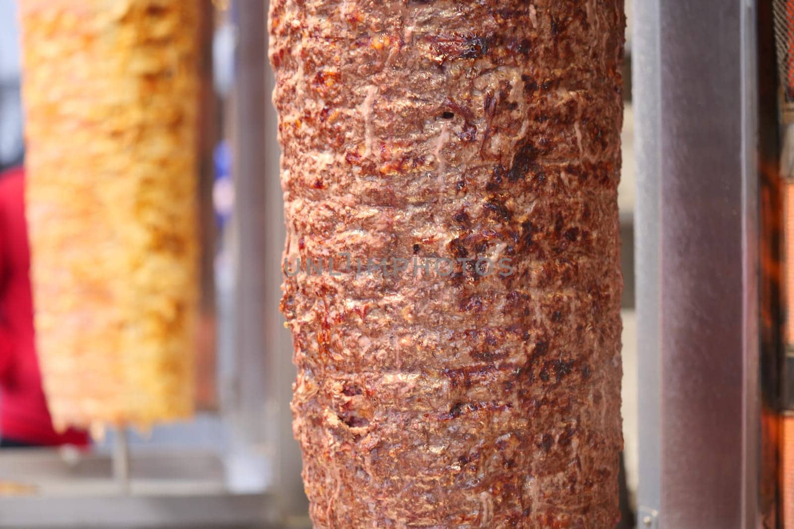 Juicy layers of seasoned meat slowly cook on a vertical grill at dusk.