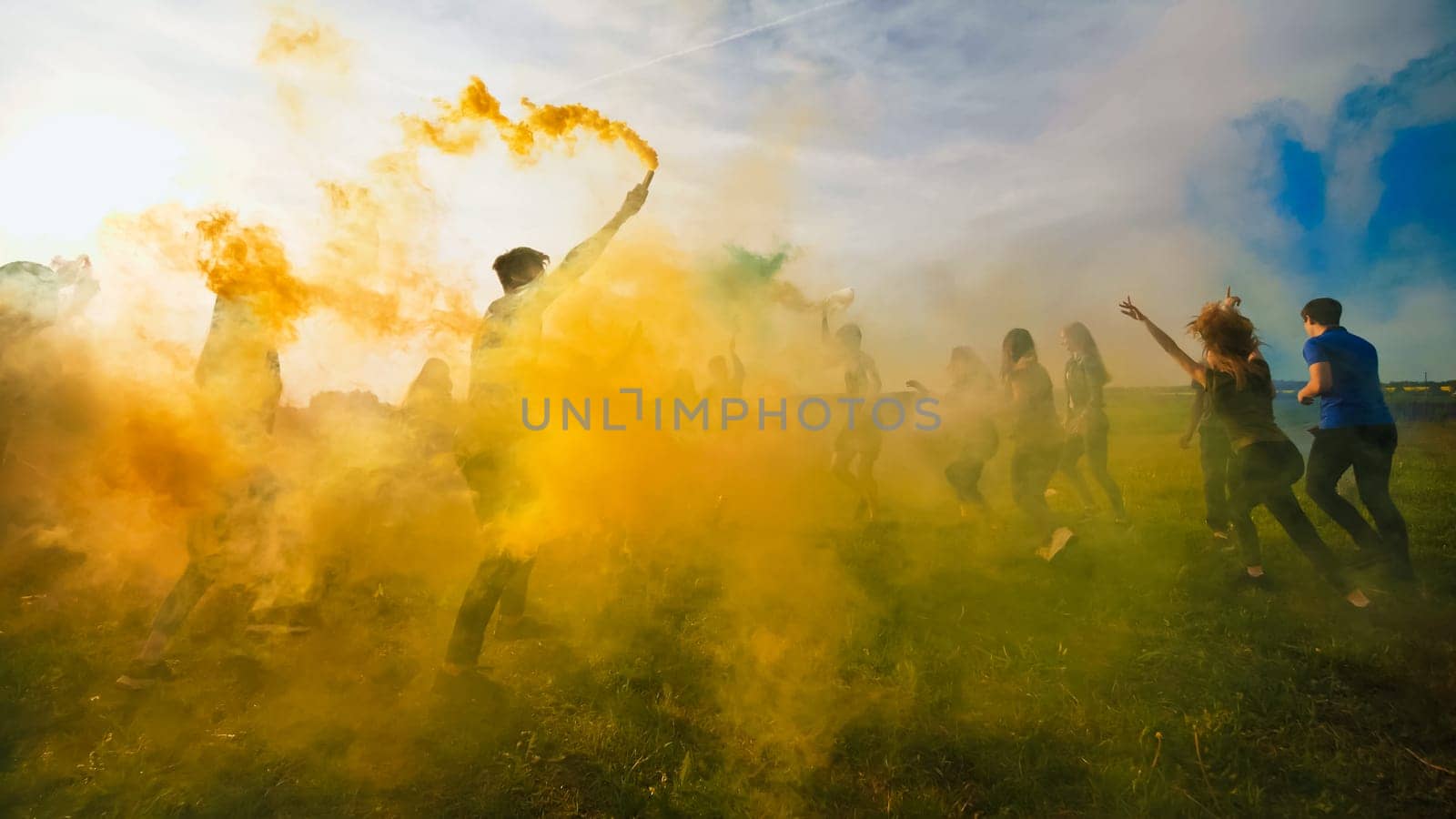 Happy friends girls waving colorful smoke at sunset