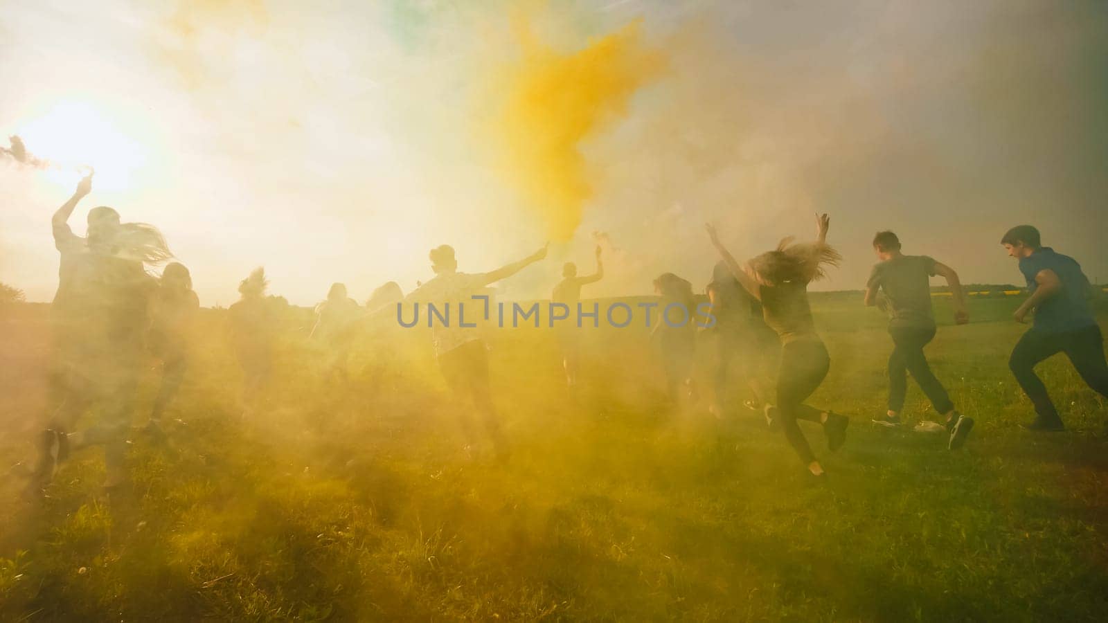 Happy friends girls waving colorful smoke at sunset