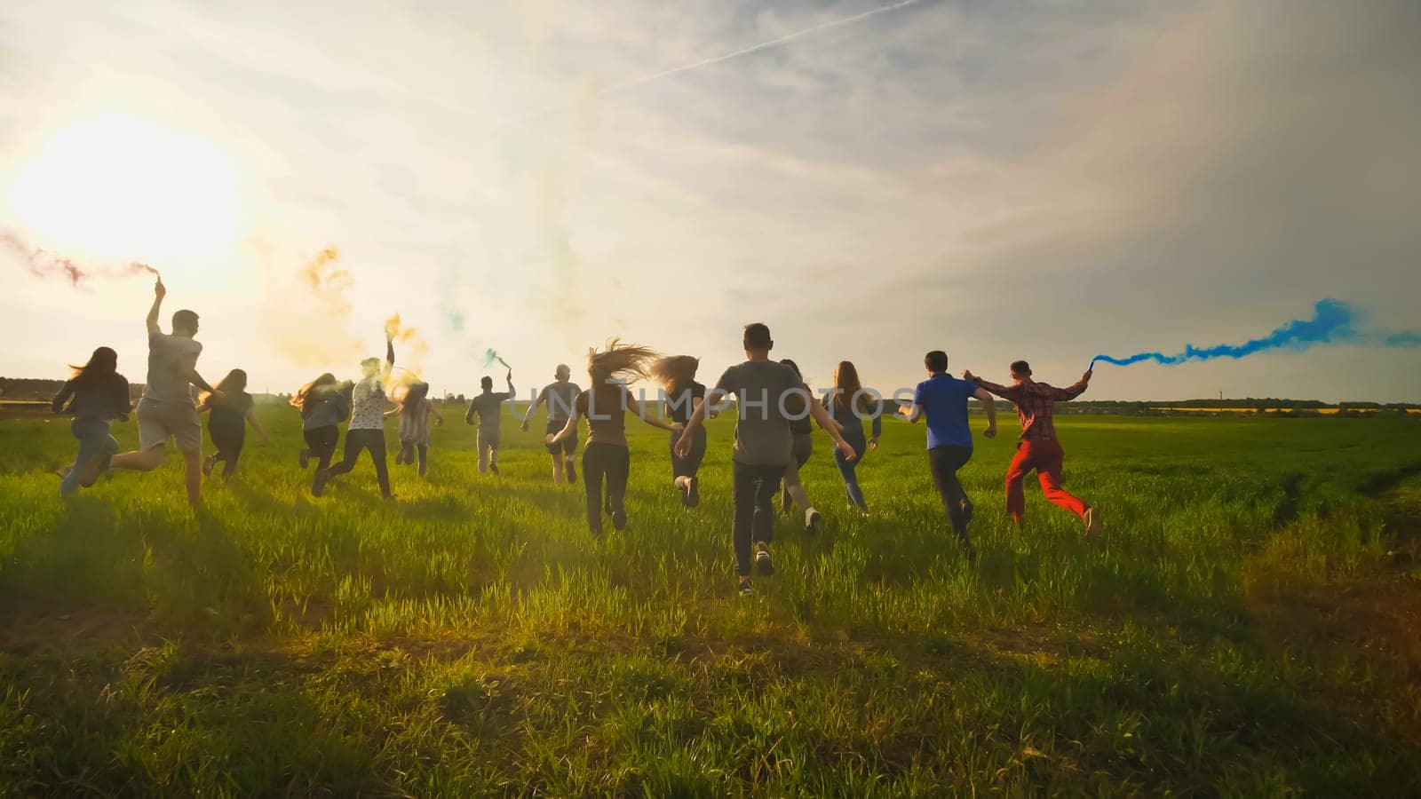 Happy friendly friends run across the field with toy planes that emit colored smoke