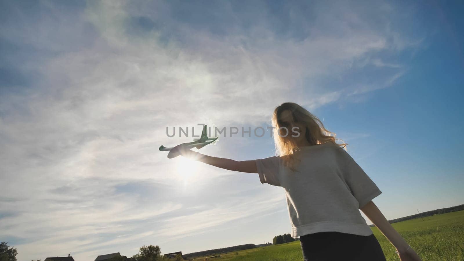A young girl with a toy airplane smokes colorful smoke on a summer evening