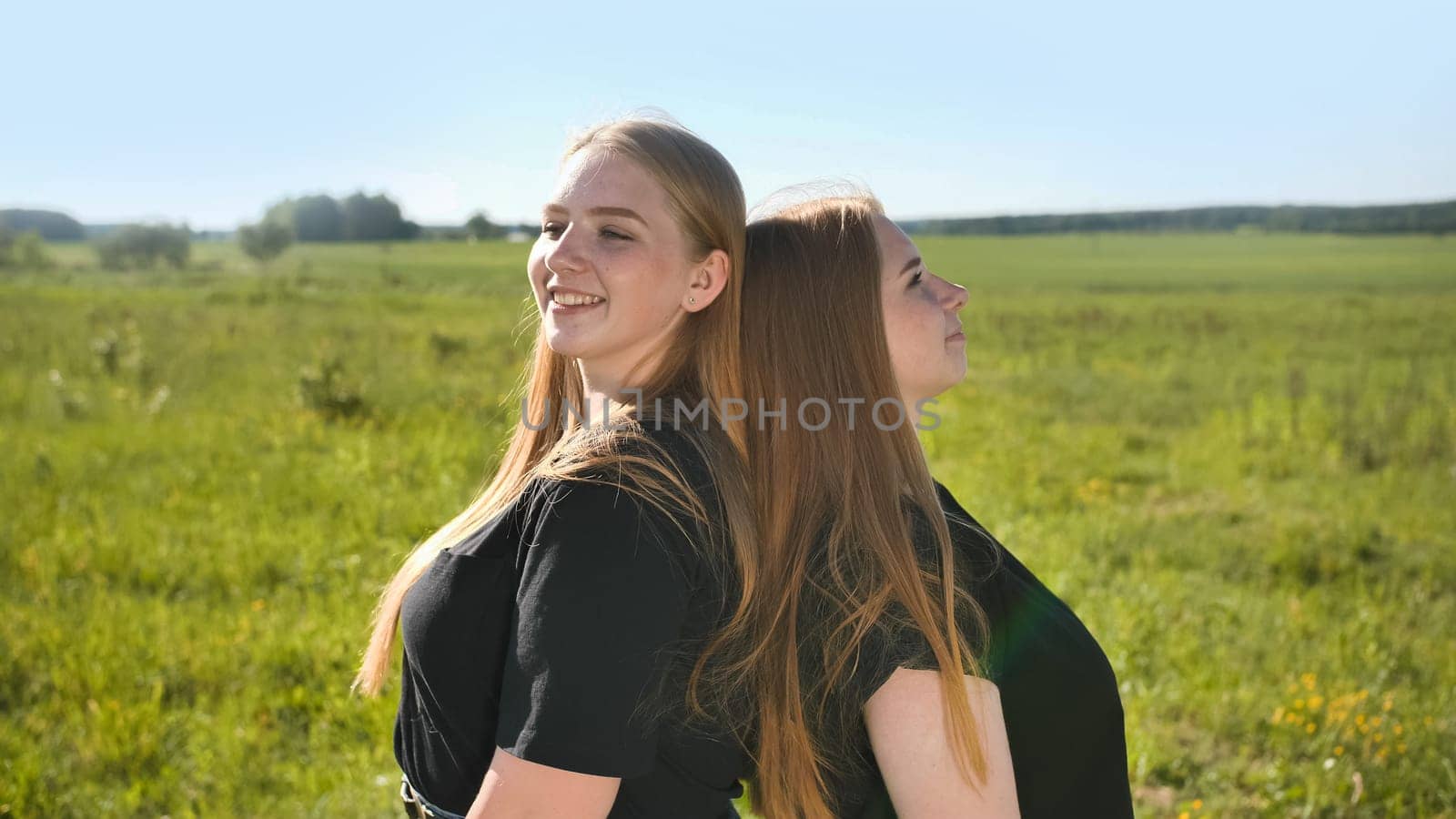 Portrait of two twin sisters in the field on a warm summer day.