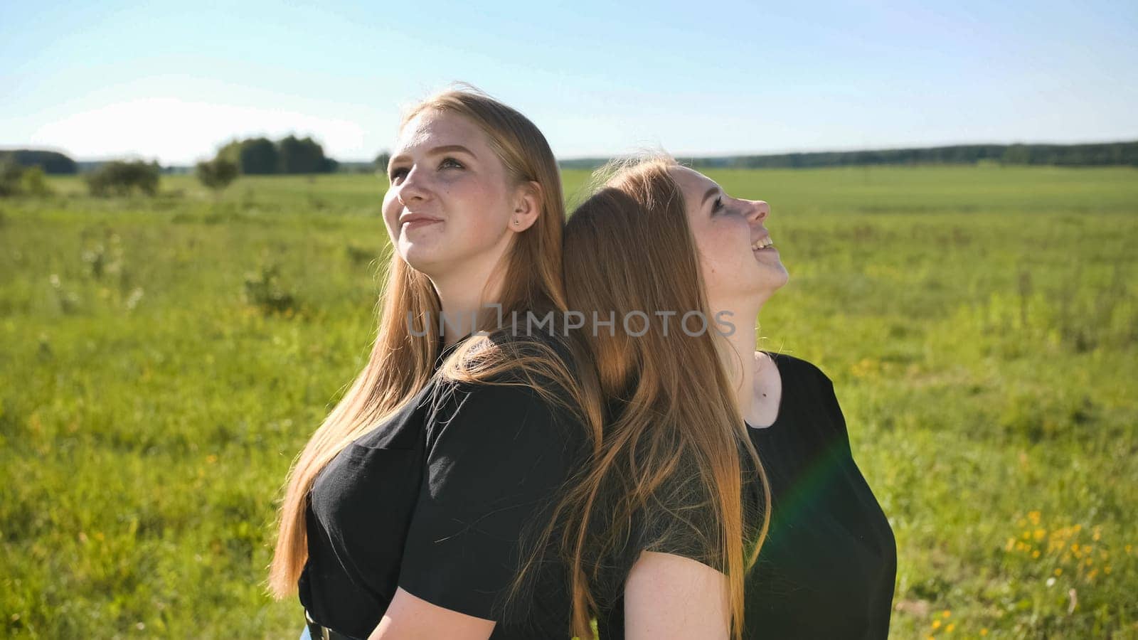 Portrait of two twin sisters in the field on a warm summer day.