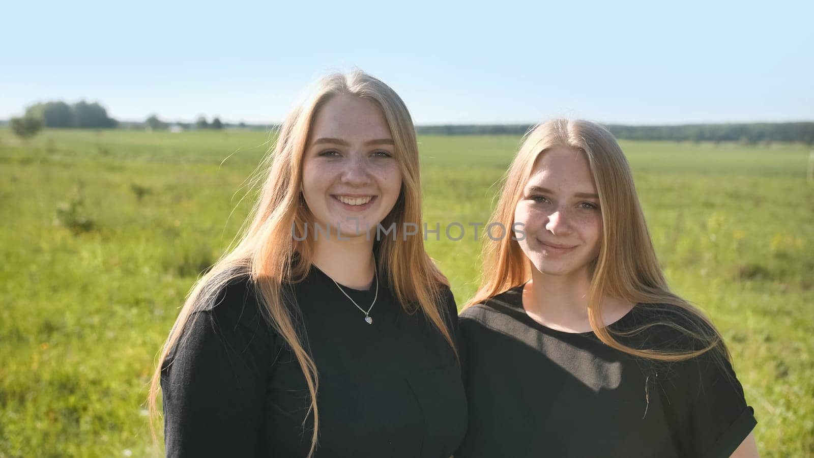 Portrait of two twin sisters in the field on a warm summer day.