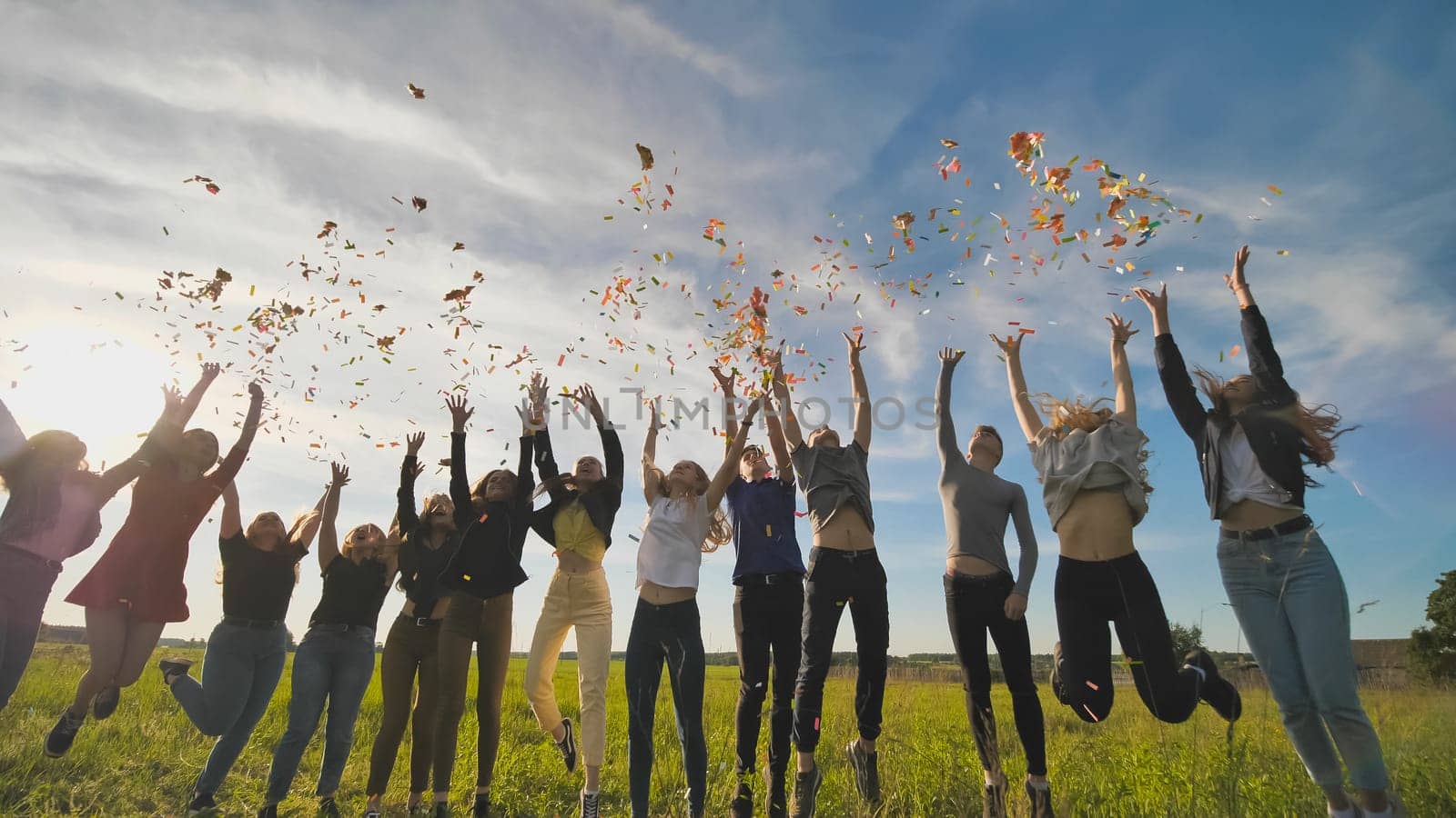 A group of friendly friends toss up candy at sunset in a field